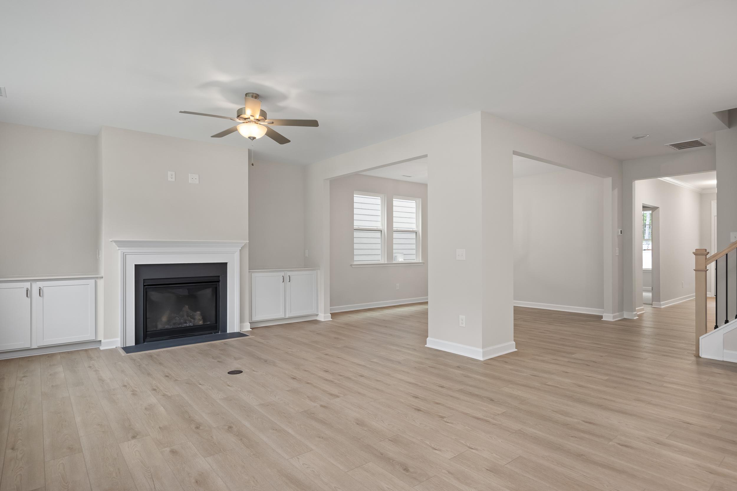 Spacious open-concept family room in The Beech A featuring gas fireplace, ceiling fan, hardwood floors