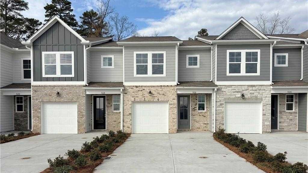 Row of modern gray 2-story townhomes with brick accents, garages, and landscaping in Stegall Village, Emerson, Georgia