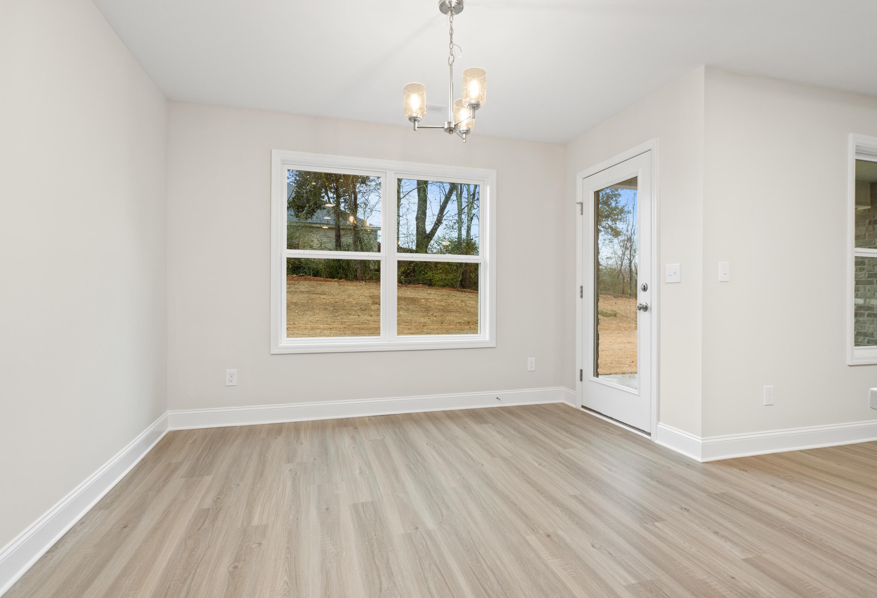 Spacious dining room in The Asheville by Davidson Homes featuring large window, glass patio door, and light oak luxury vinyl plank flooring
