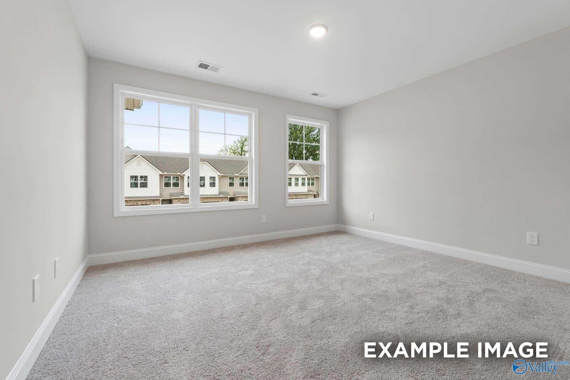 Bright secondary bedroom with neutral gray walls, carpeted floor, and large windows overlooking neighborhood in The Camden D, Huntsville, AL