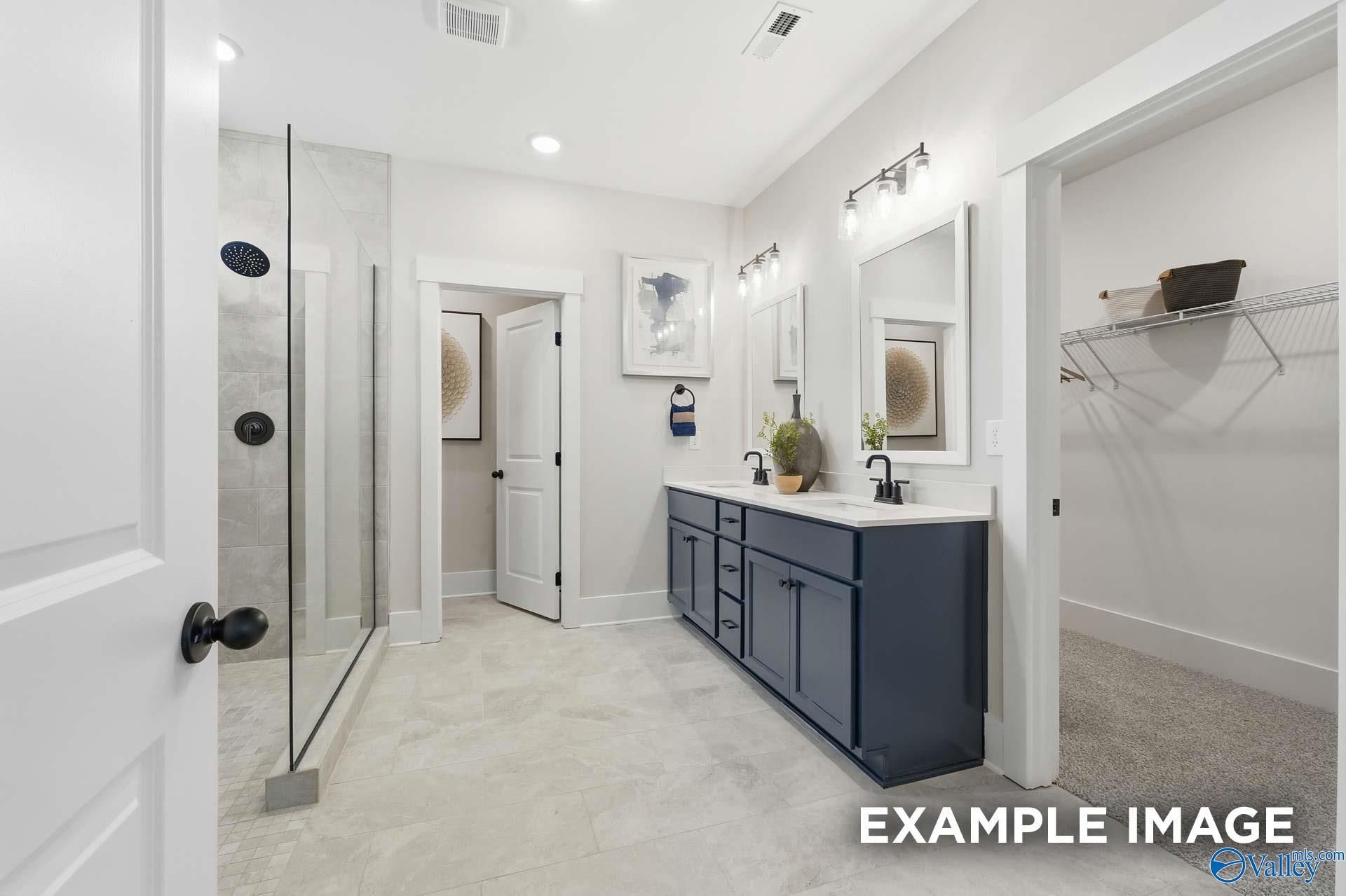 Primary bathroom with navy double vanity, glass walk-in shower, and dual mirrors in Davidson Homes The Hibiscus F, Arab, Alabama