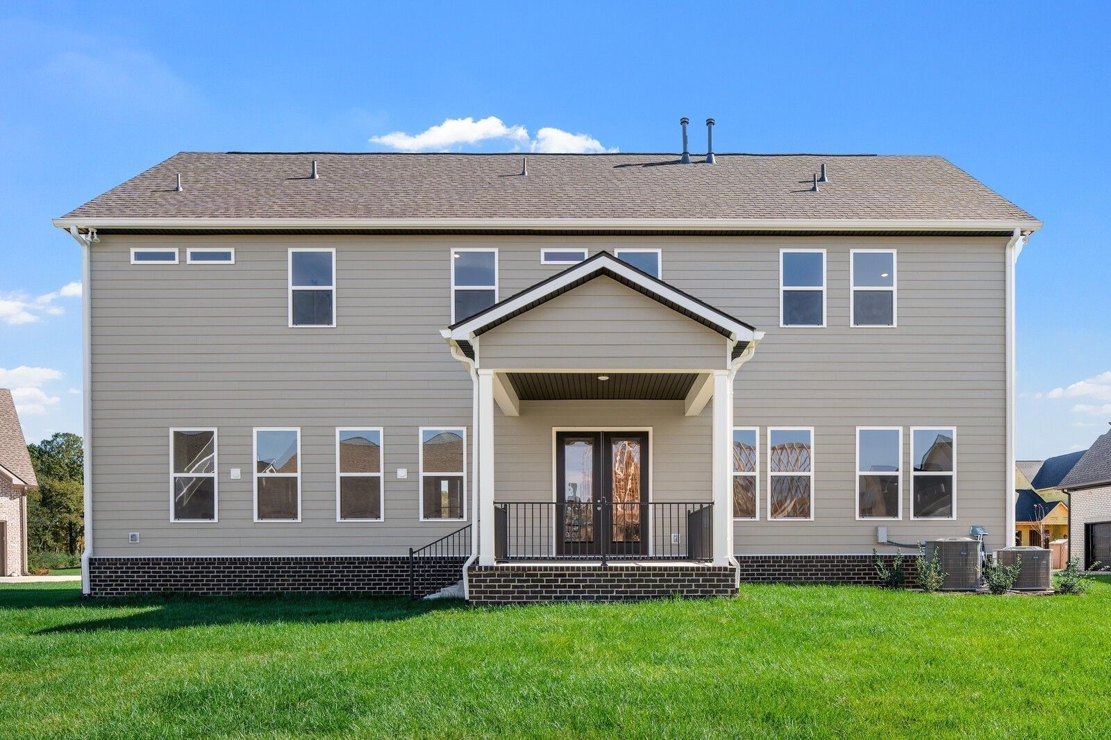 Two-story beige Alston A home with covered front porch, large windows, and lush green lawn in Shelton Square, Murfreesboro, Tennessee