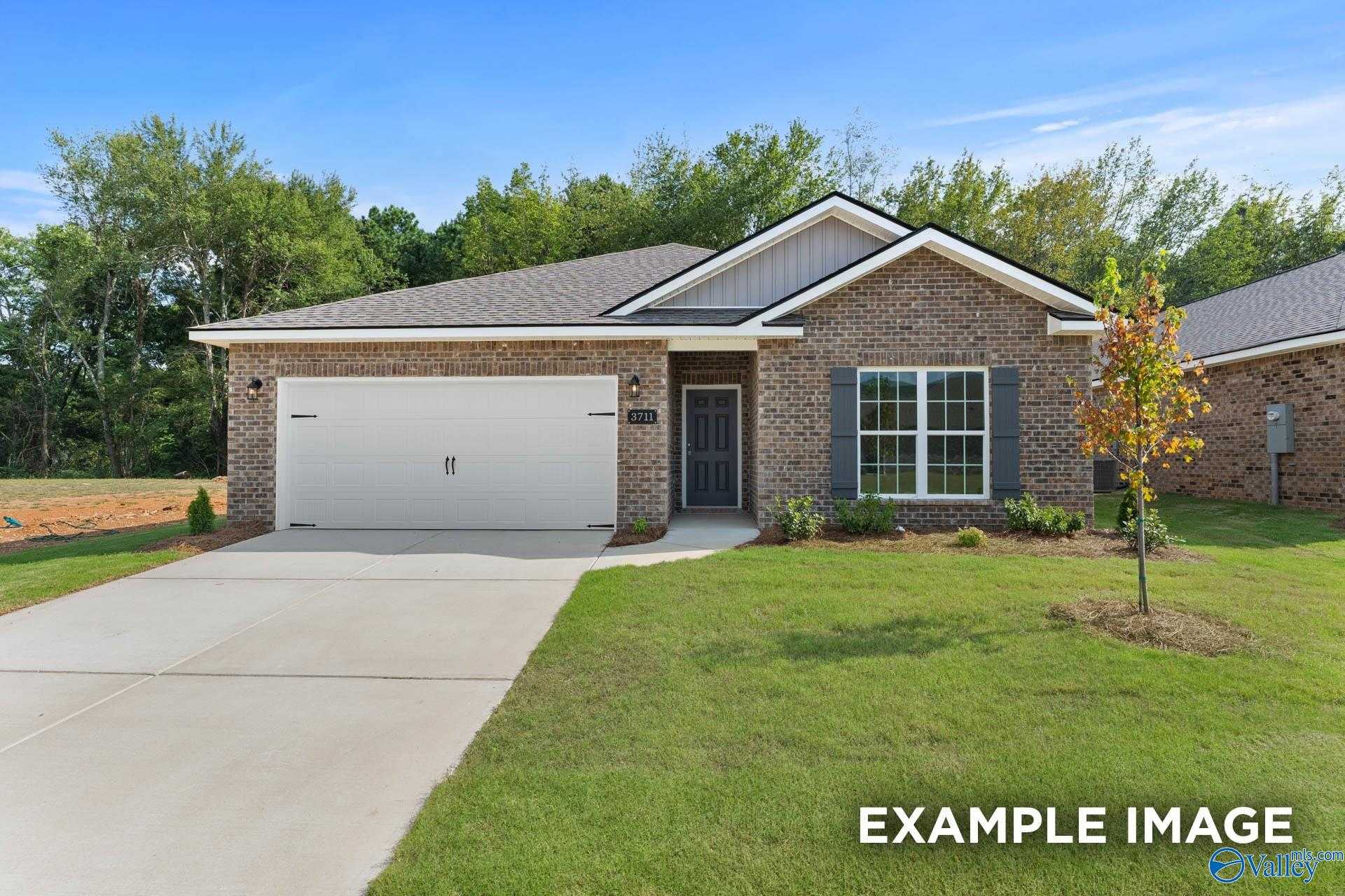Modern brick 1-story home with 2-car garage, driveway, and lush front yard in Ramsay Cove, Owens Cross Roads, Alabama