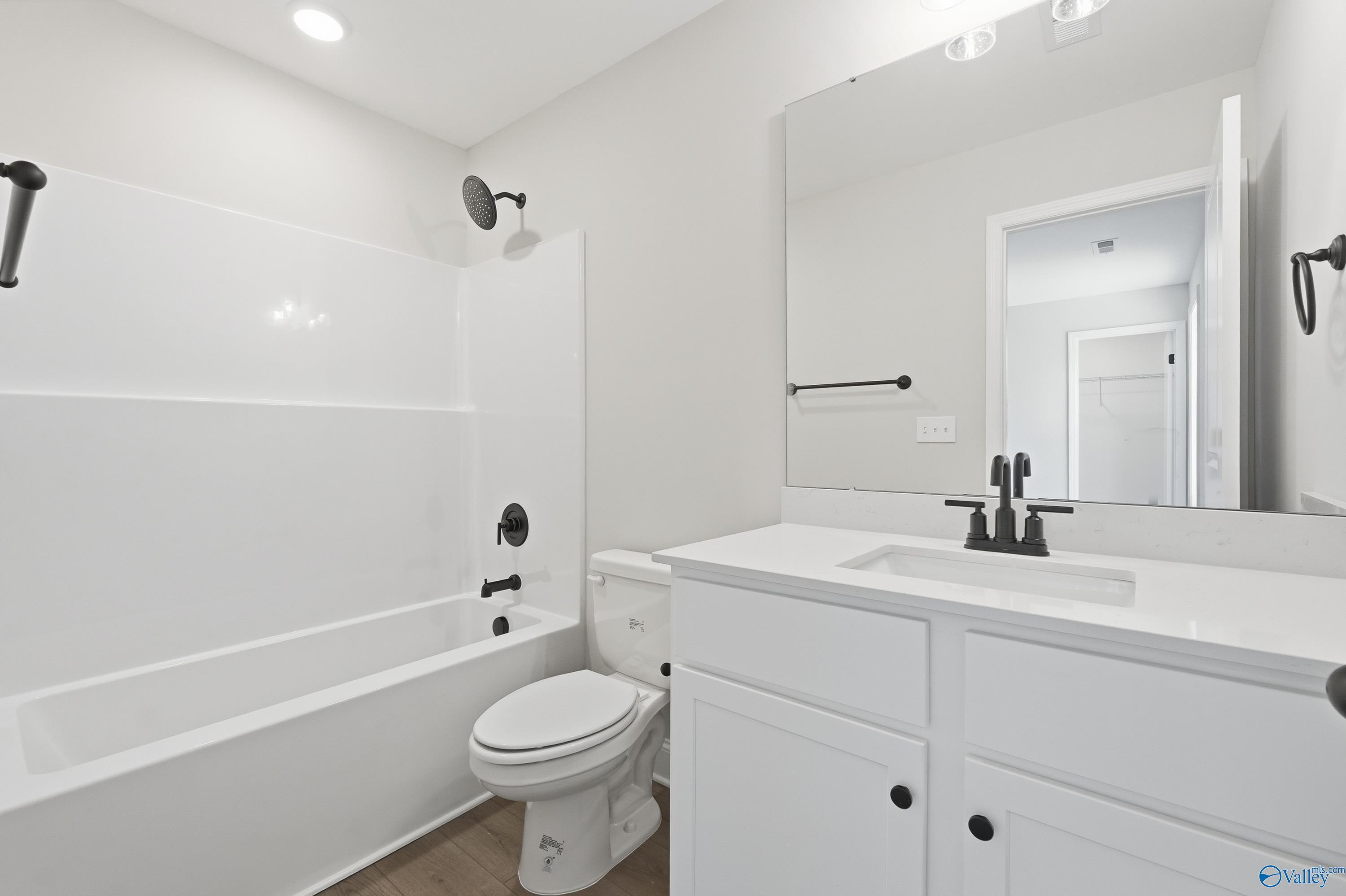 Spacious white master bathroom with subway tile shower, soaking tub, vanity, and black fixtures in The Chelsea D by Davidson Homes, Cullman, AL