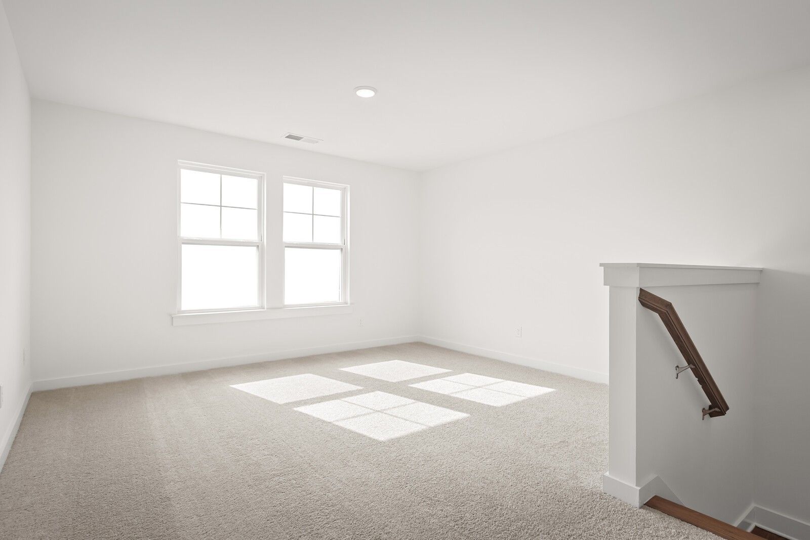 Bright upstairs bedroom with large windows, natural sunlight, beige carpet, and wooden staircase in The Logan C home, Gallatin, TN