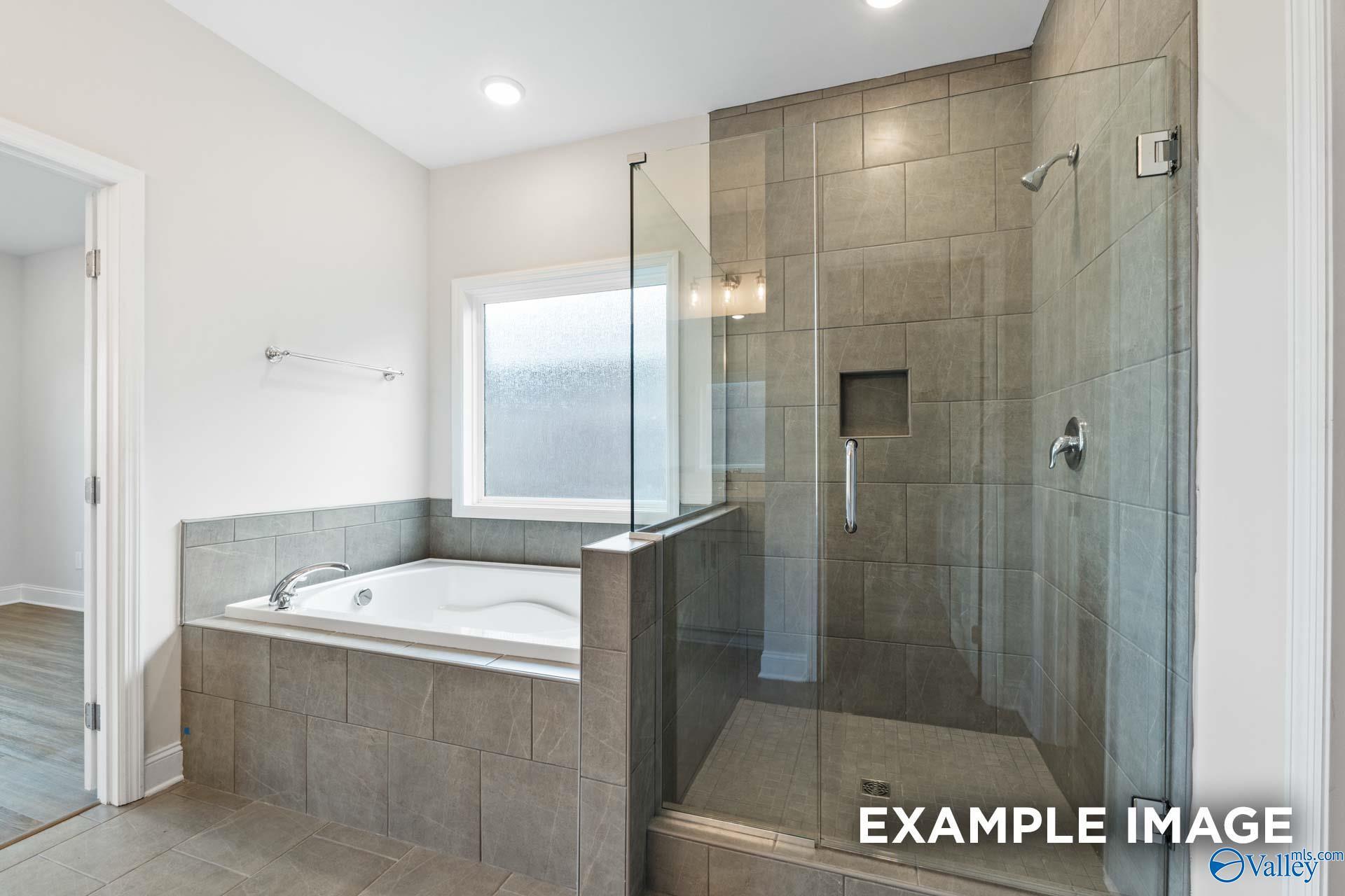 Luxurious master bathroom with soaking tub, frameless glass shower, and tiled accents in Davidson Homes The Montgomery, Hartselle