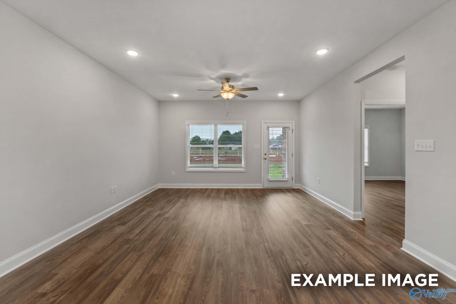 Bright living room with hardwood floors, ceiling fan, large windows, and sliding doors in Davidson Homes The Cumberland B, Decatur, AL