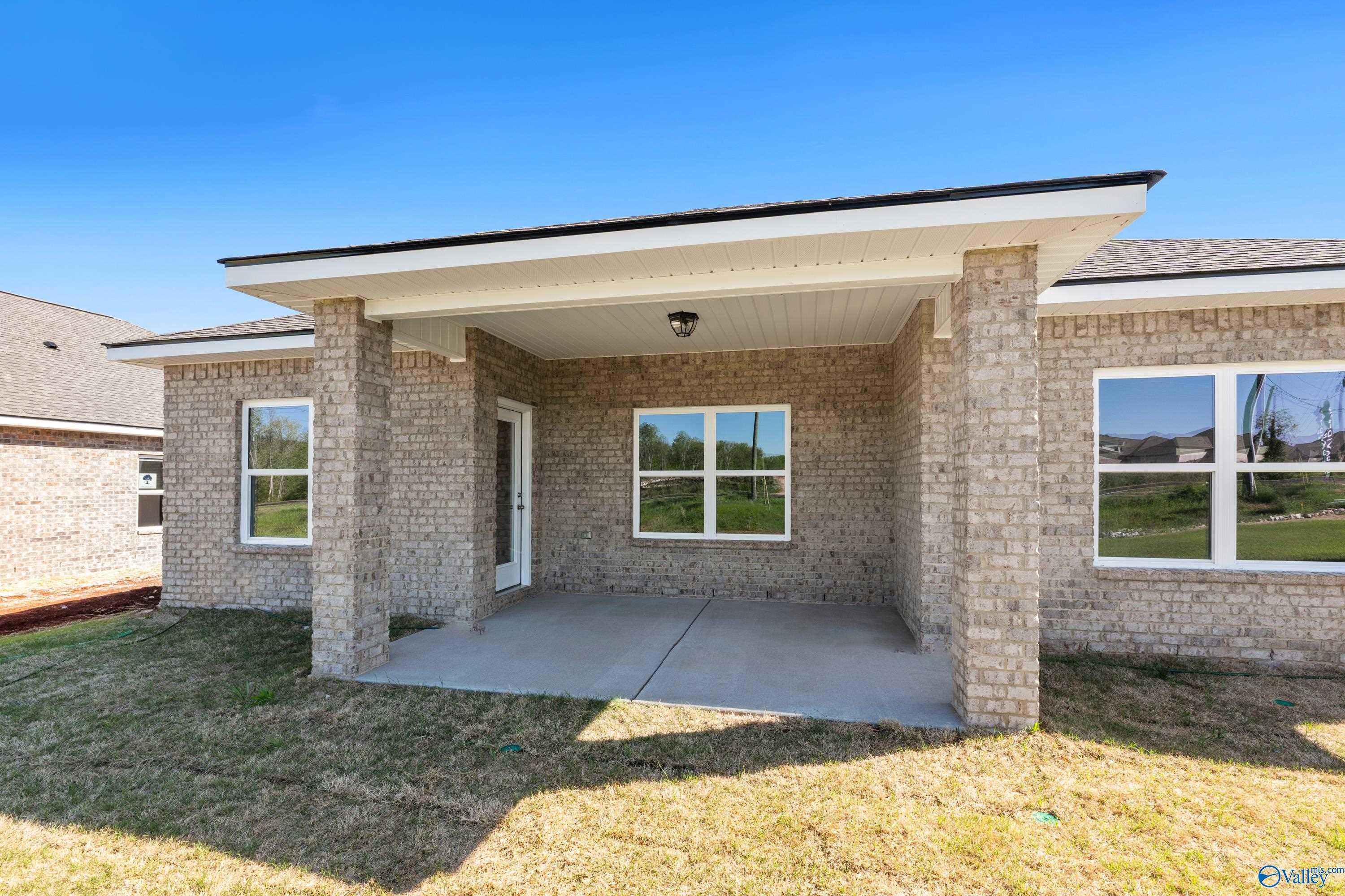 Brick front exterior with covered porch, columns, and large windows on The Asheville C 3-bedroom home in The Meadows, Athens, Alabama