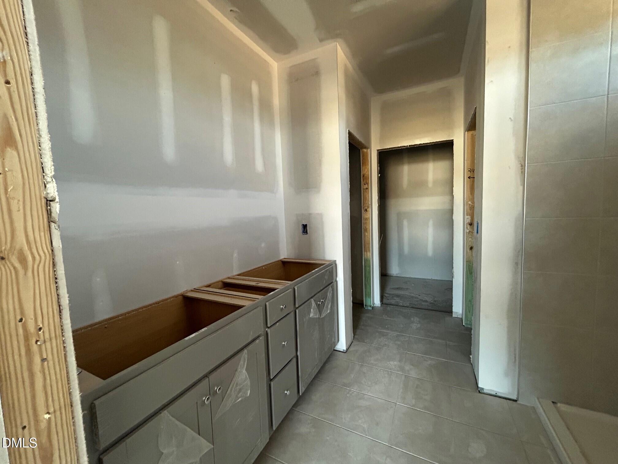 Unfinished master bathroom with double gray vanity cabinets and tiled shower in The Daphne D, Lillington, NC