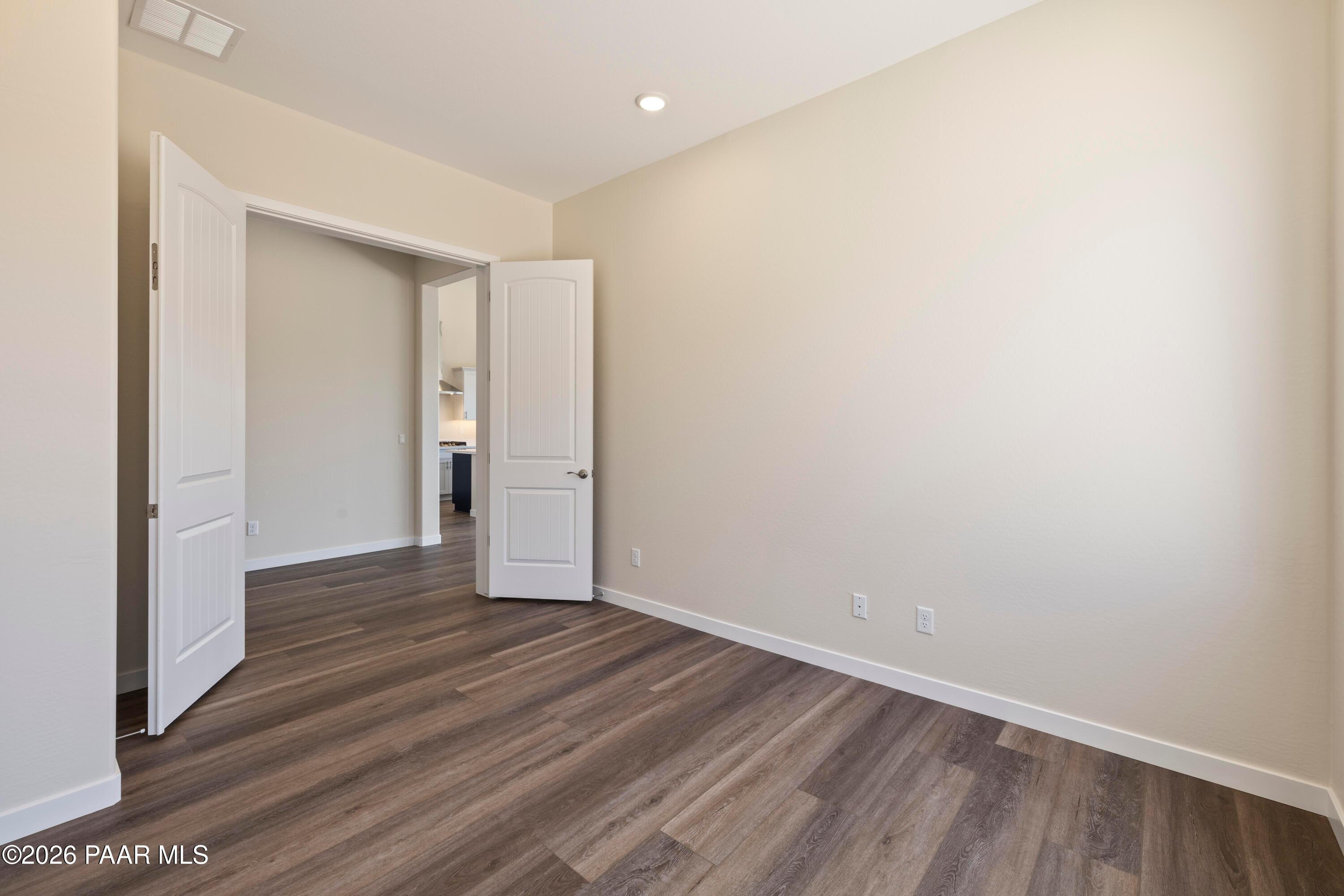 Open double doors revealing adjacent space in bright room with beige walls, recessed lights, luxury plank flooring, Soleil E Prescott home