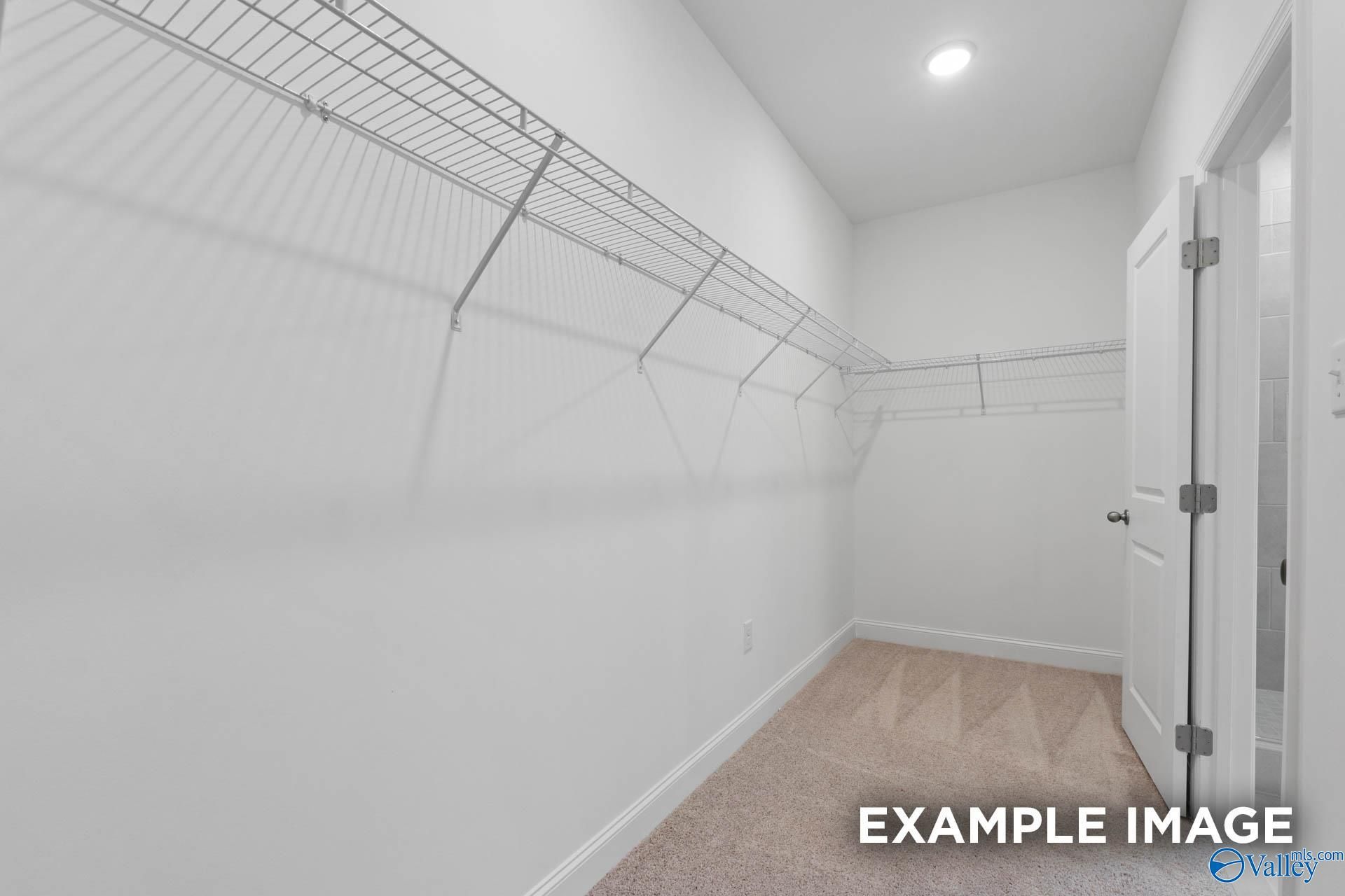 Spacious walk-in closet with wire shelving and white walls in The Montgomery 3-bedroom home by Davidson Homes, Meridianville, Alabama