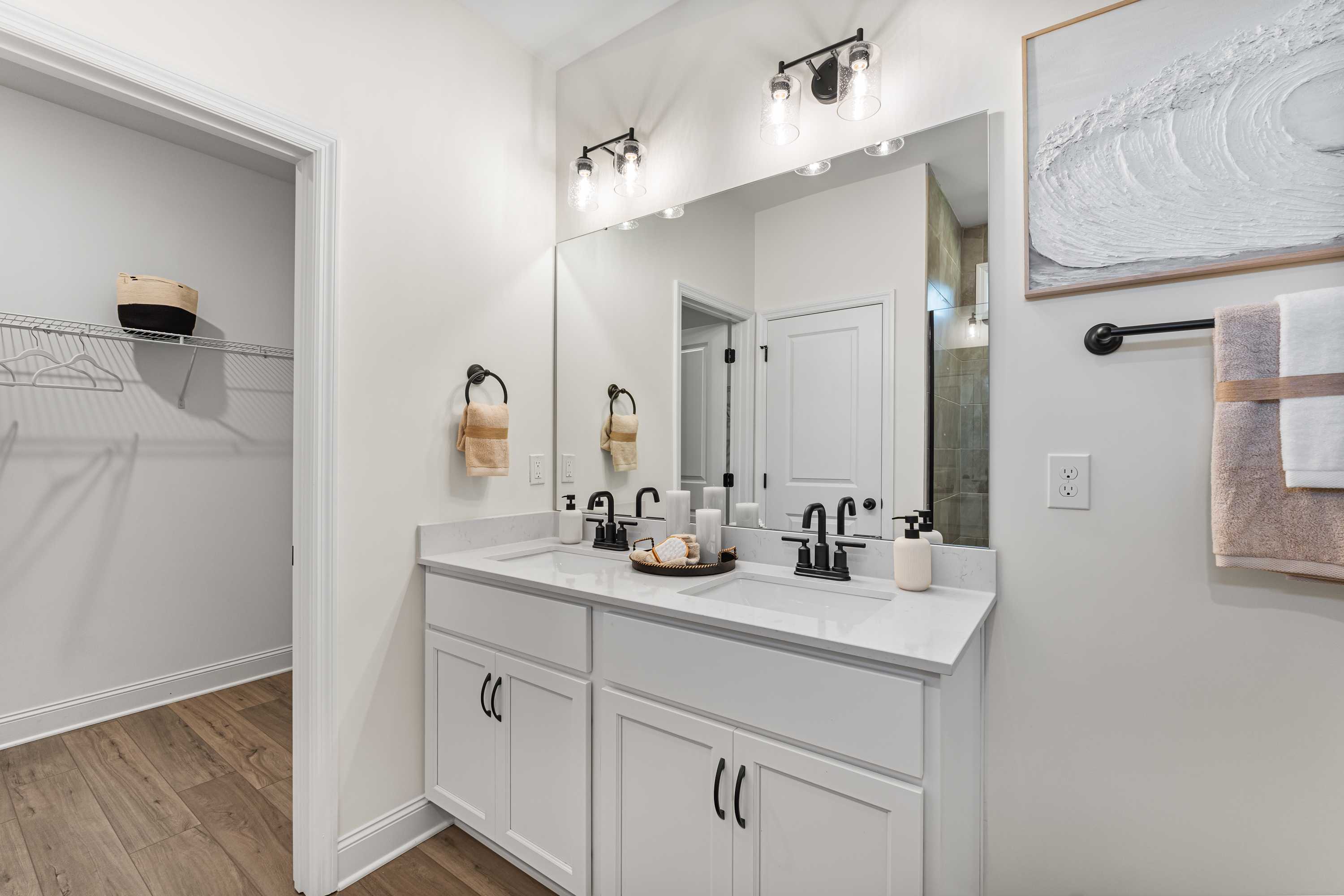 Spacious primary bathroom at Lynn Meadows in Meridianville AL with double white vanity, frameless mirror, and walk-in closet