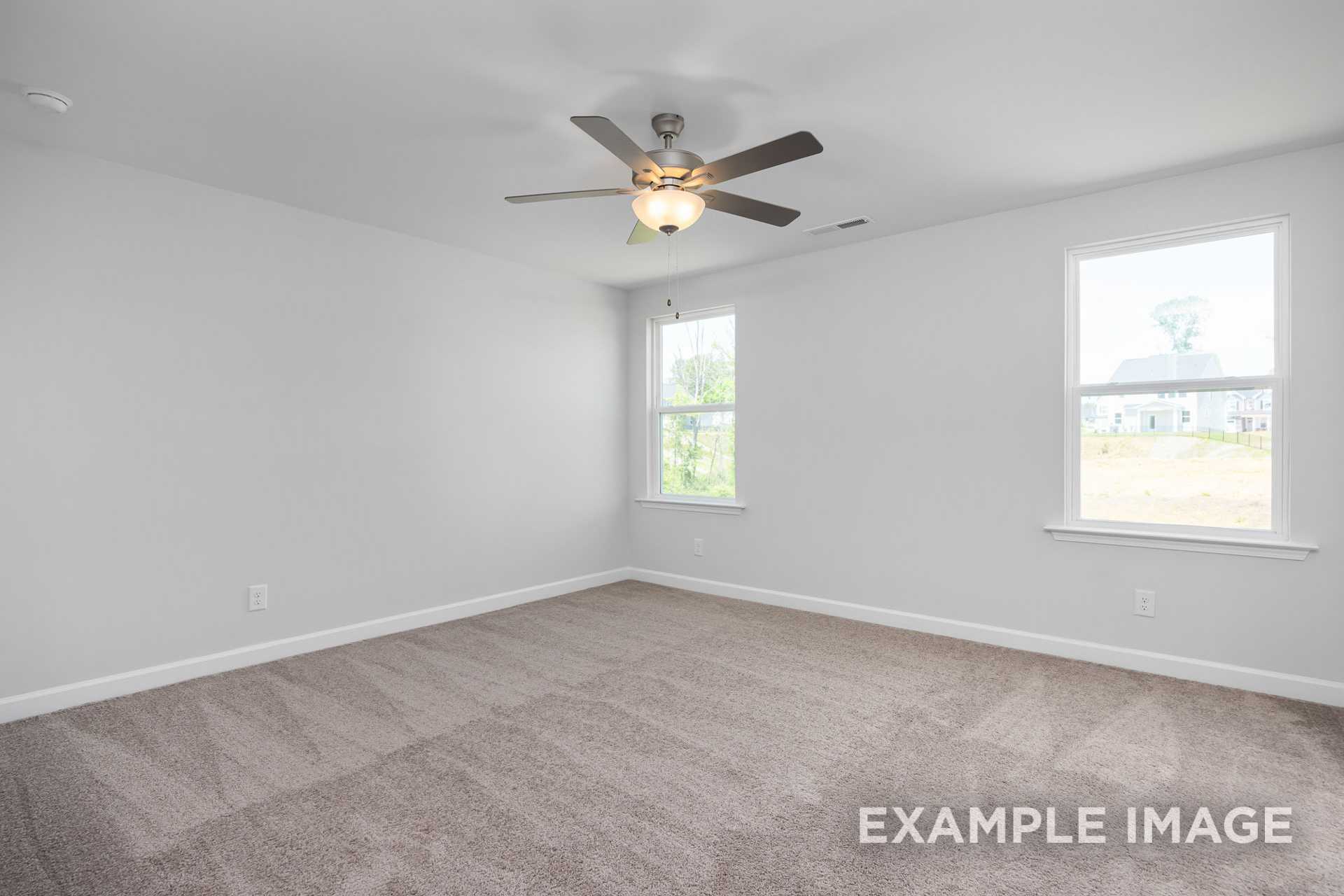 Spacious upstairs bedroom in Gavin C by Davidson Homes featuring ceiling fan, white walls, beige carpet, and large windows