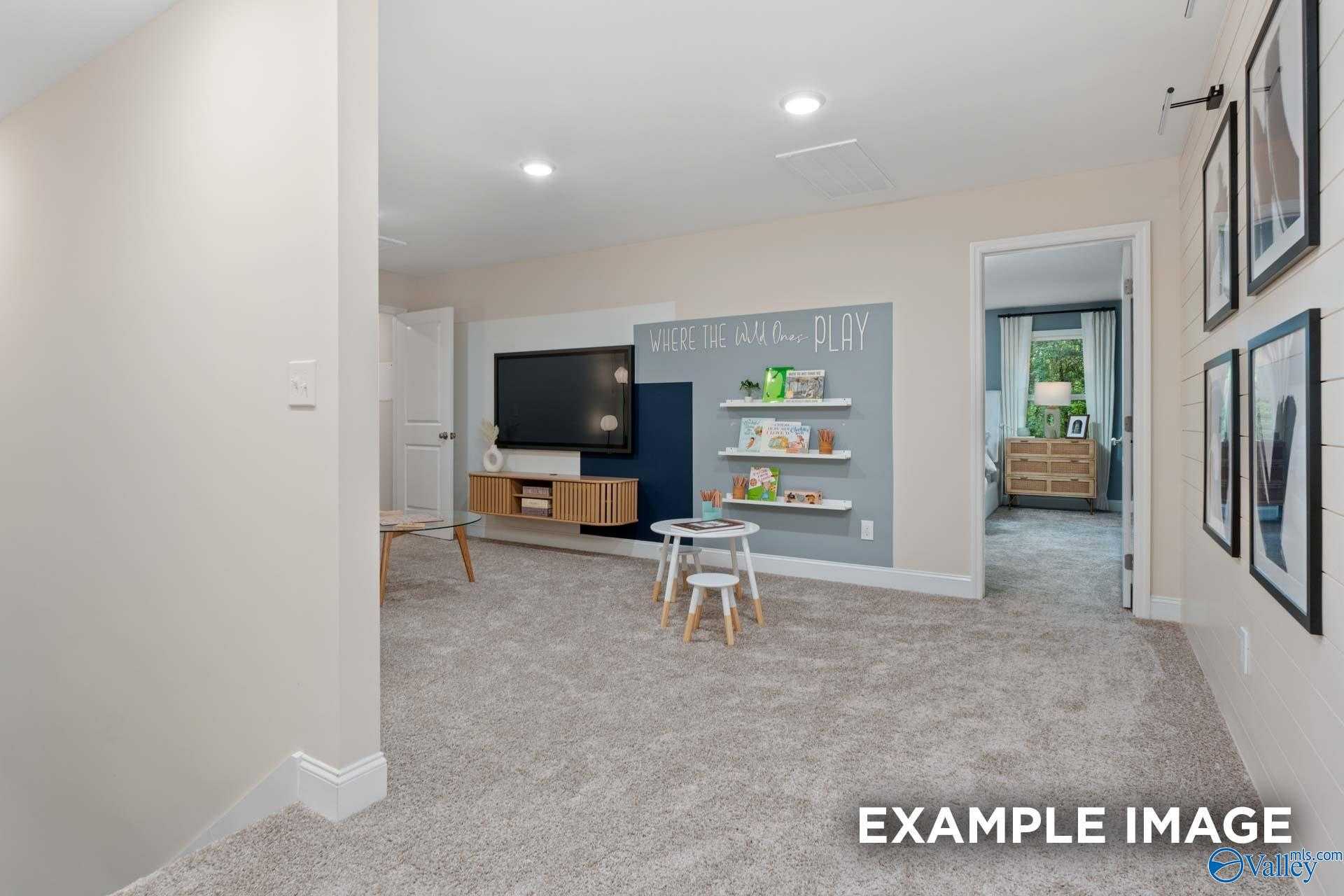 Cozy children's playroom with mounted TV, toy shelves, kids' table, and "Live Laugh Play" wall in Davidson Homes The Camden B, Huntsville AL