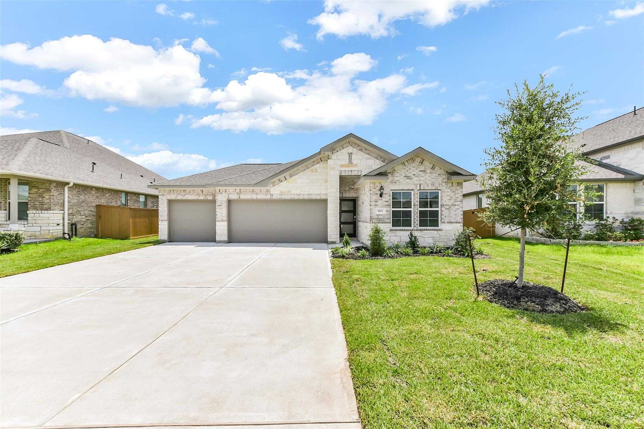 Davidson Homes The Laguna C single-story 3-car garage home exterior with brick facade, driveway, and lush lawn in Sierra Vista, Rosharon, Texas