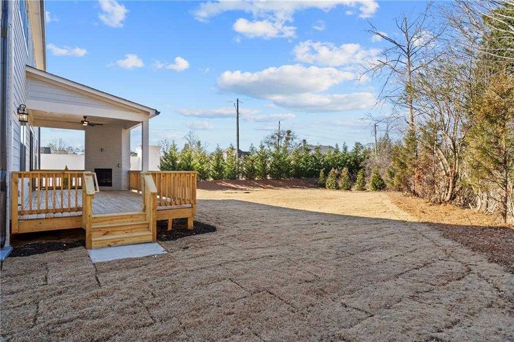 Covered wooden deck and porch on white-sided home with gravel backyard and surrounding pines in Davidson Homes The Arlington A, East Cobb, Georgia