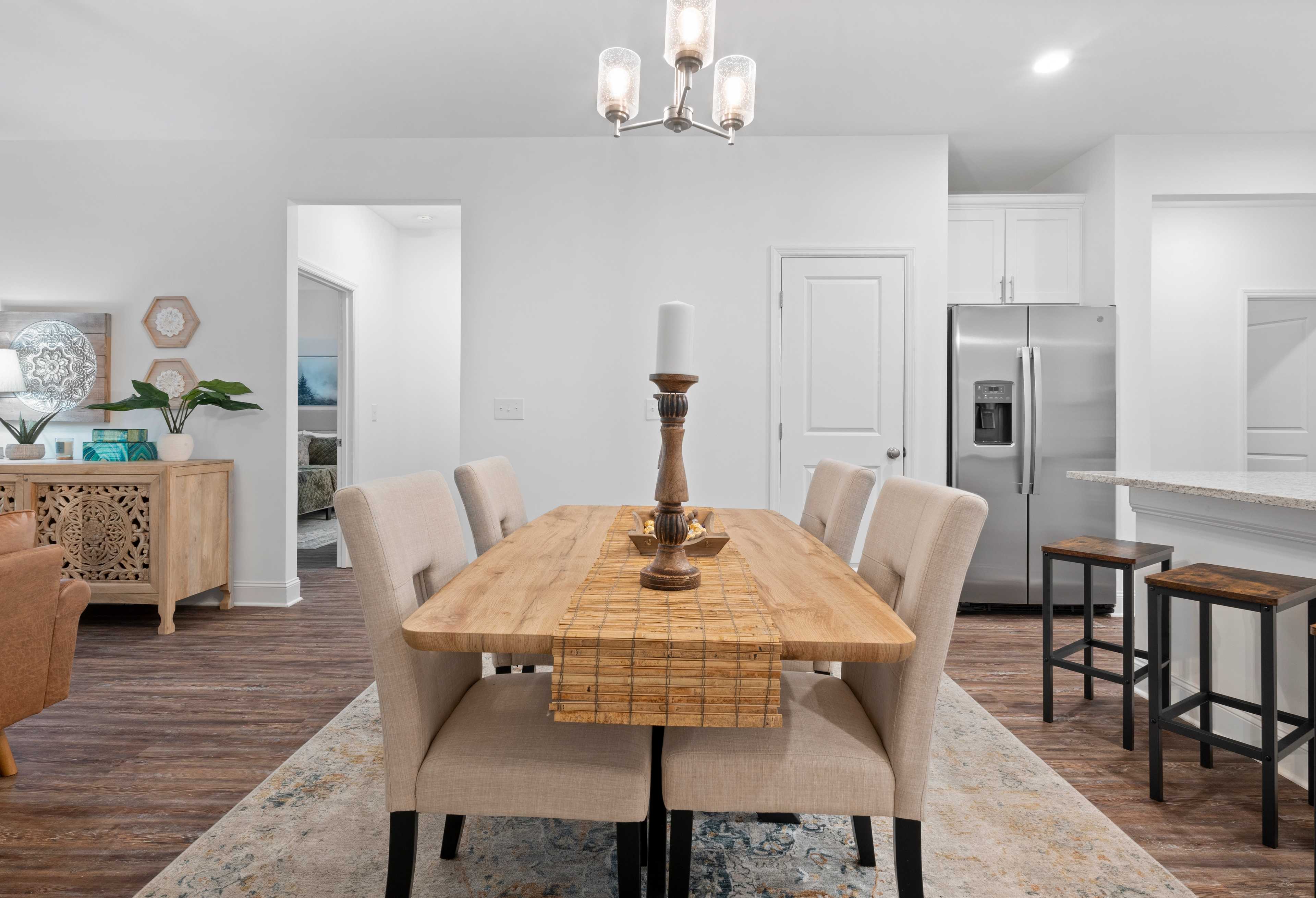Spacious dining area in The Cumberland home design with wooden table, chandelier, and open kitchen island