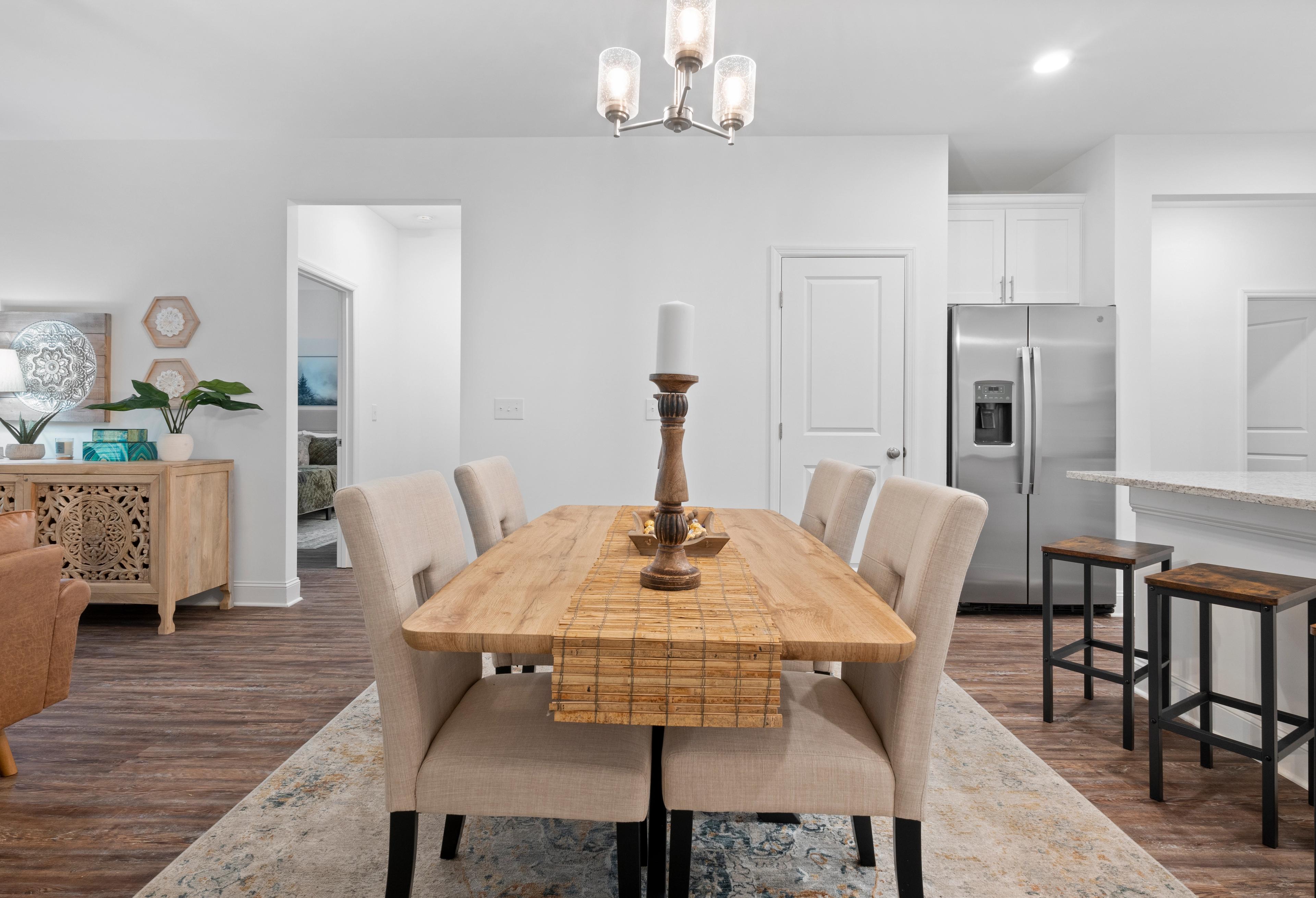 Spacious dining area in The Cumberland home design with wooden table, chandelier, and open kitchen island