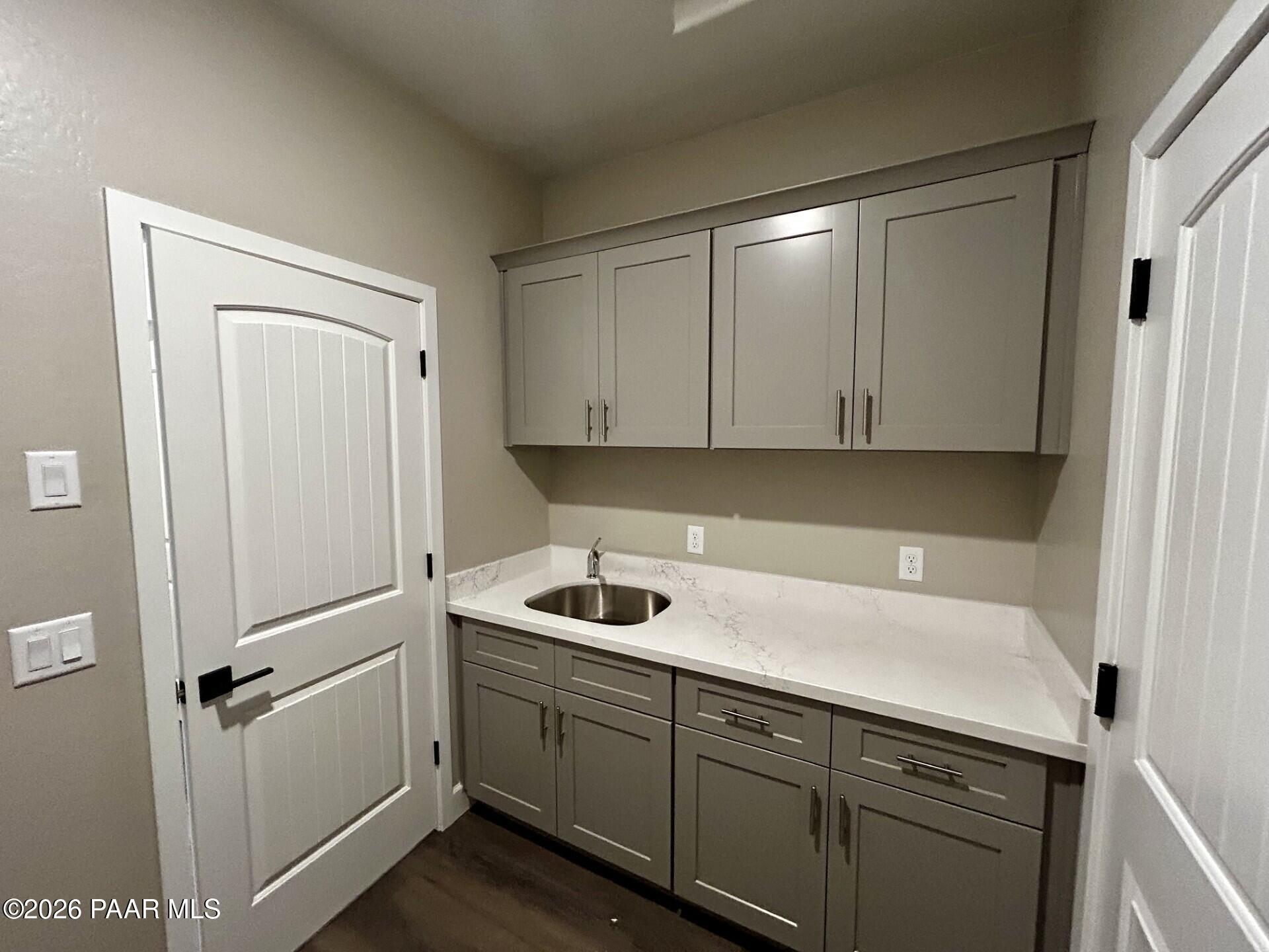 Laundry room with gray cabinets, quartz countertops, and sink in The Harmony C floor plan at Pronghorn Ranch, Prescott.