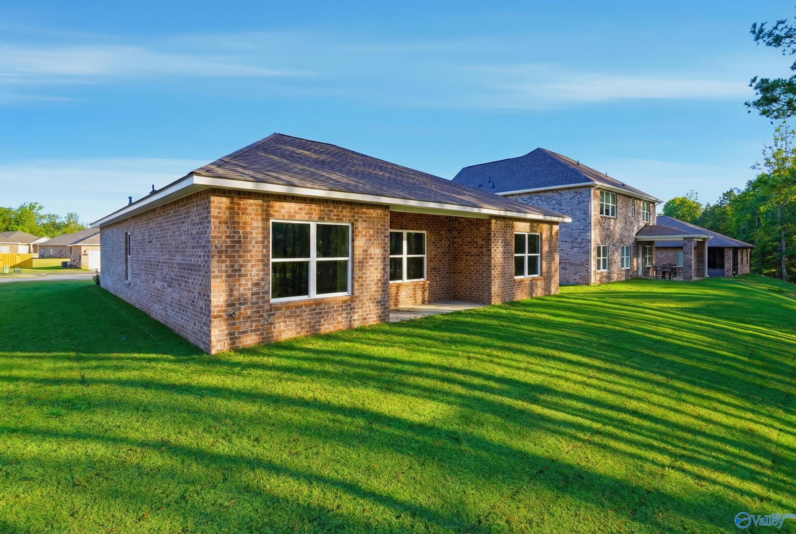 Brick single-story 3-bedroom home with 2-car garage, lush green lawn, and trees in The Highlands, Arab, Alabama