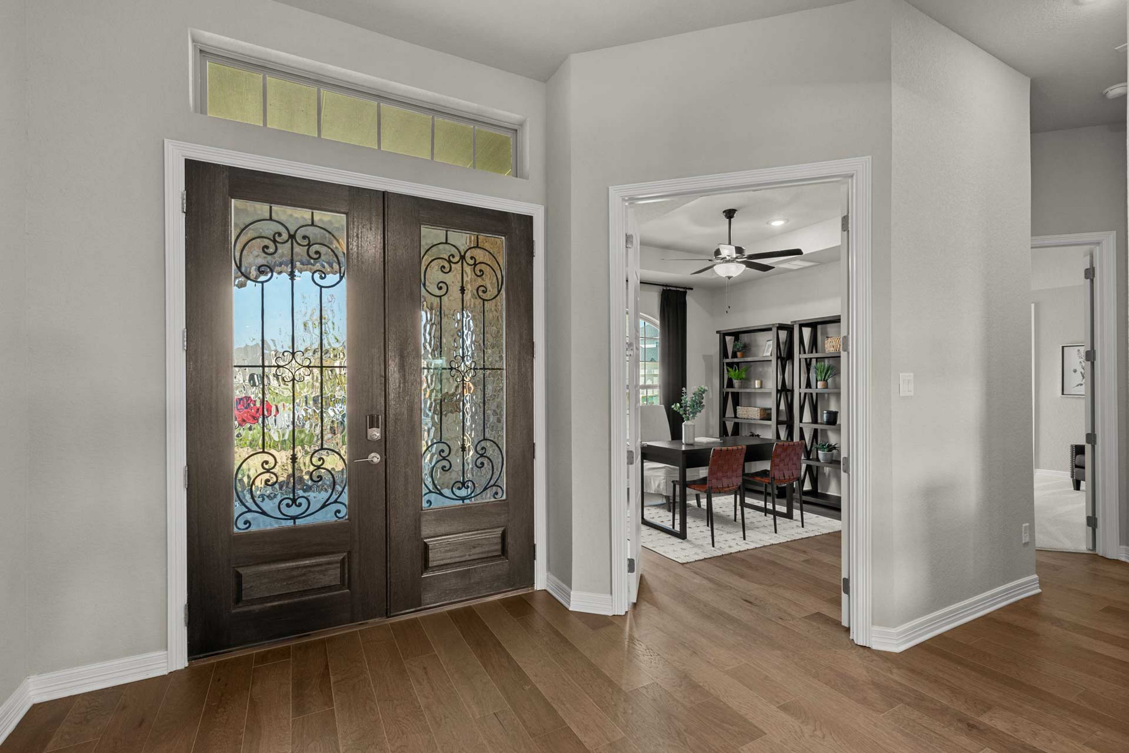 Elegant entryway with wrought iron double doors and transom window opening to dining room at Potranco Oaks in Castroville, Texas