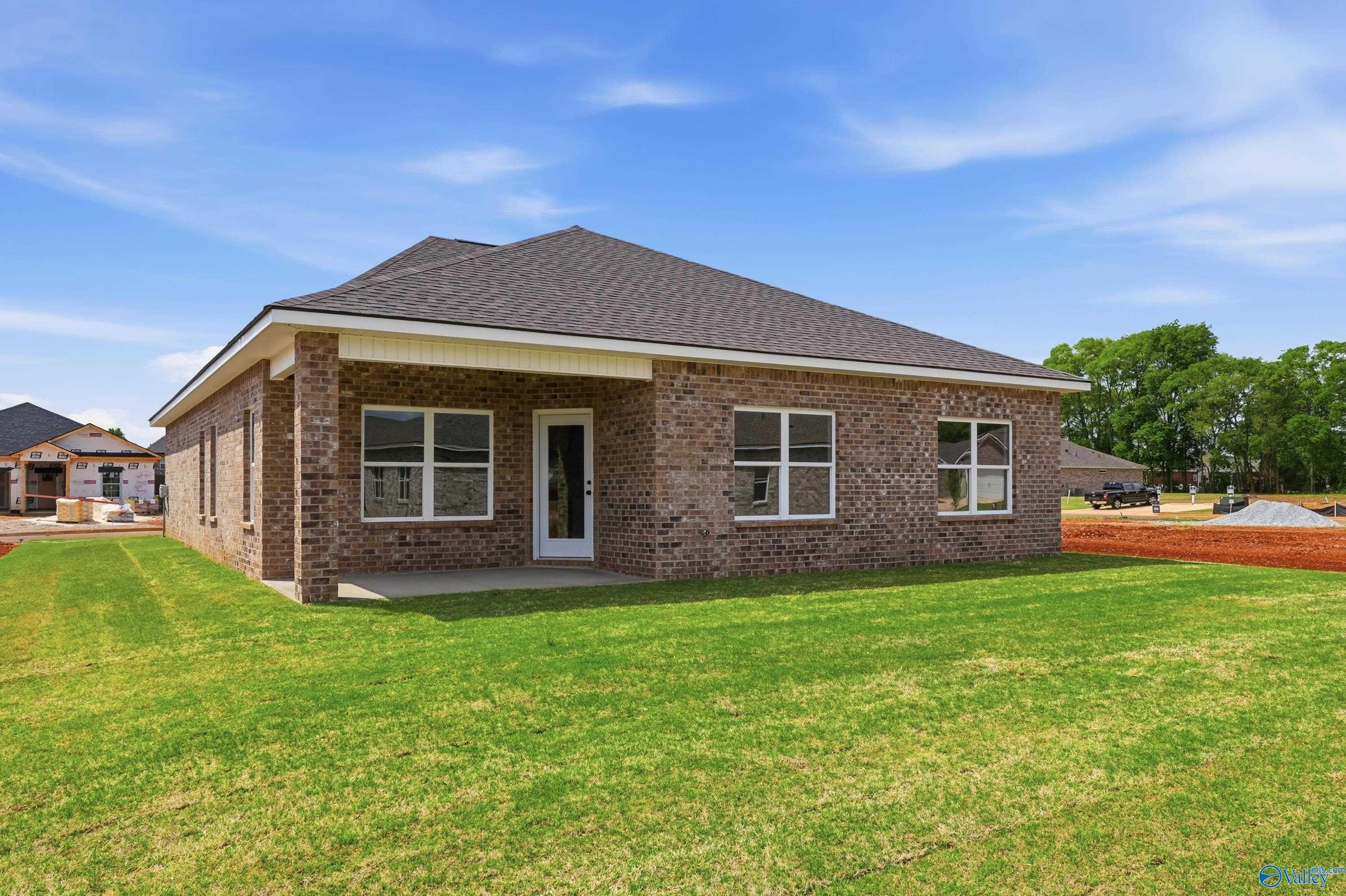 Brick single-story home with gabled roof, covered entry, large windows, and lush green lawn in Lynn Meadows, Meridianville, Alabama