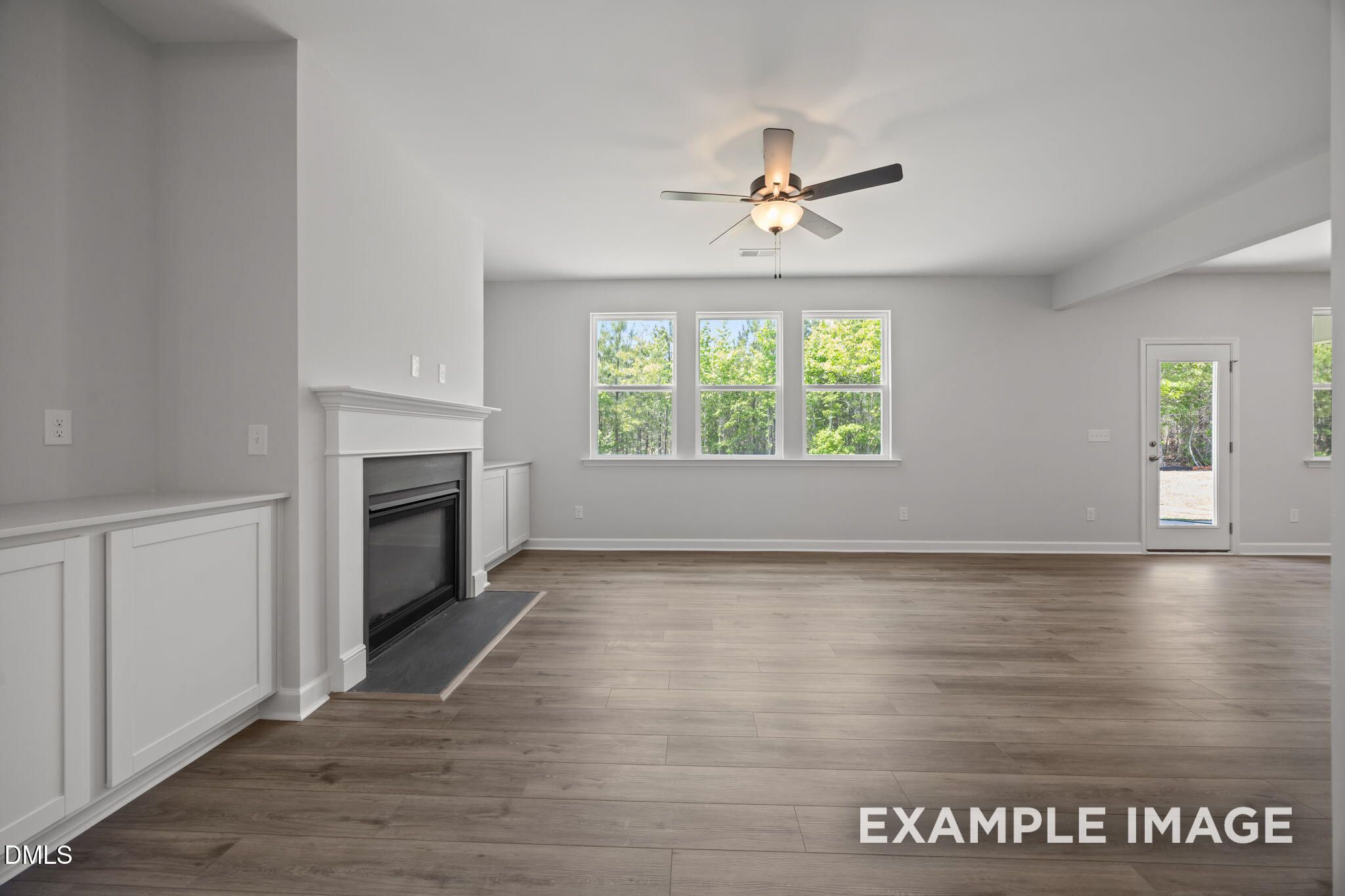 Bright living room with fireplace, luxury vinyl plank flooring, and backyard views in Davidson Homes' The Beech, Wendell Ridge, NC