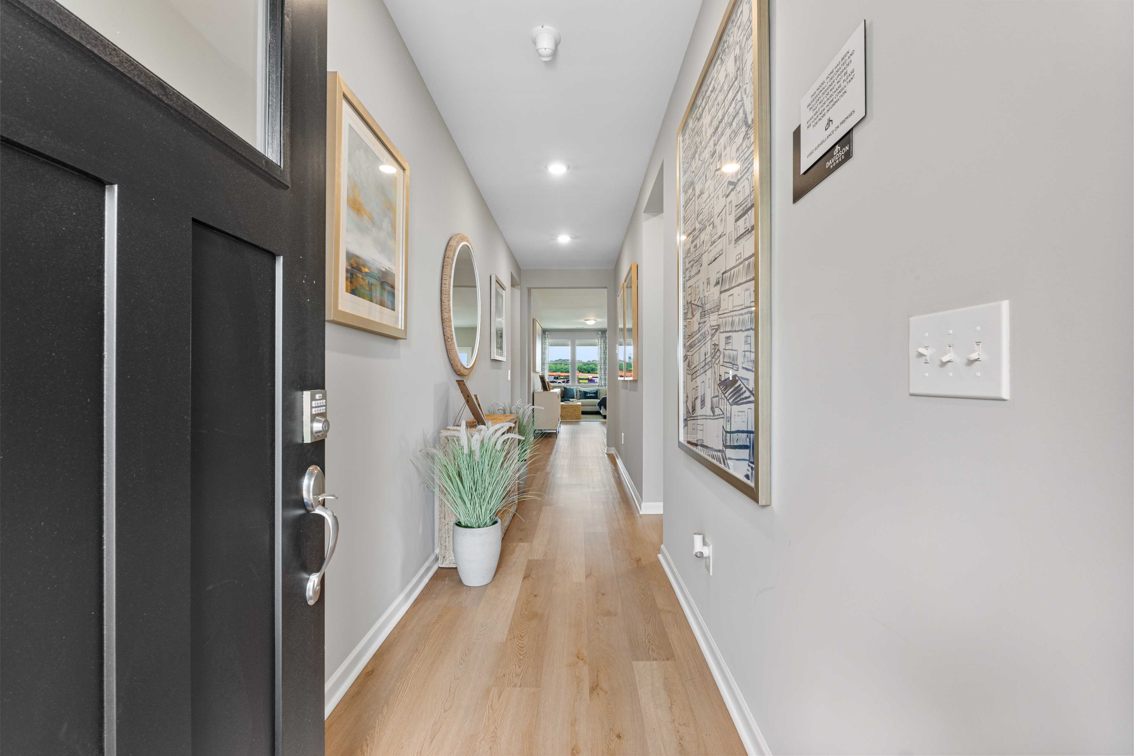 Spacious entry hallway in Forest Glen Hazel Green AL home with light oak floors, gray walls, artwork and potted plant