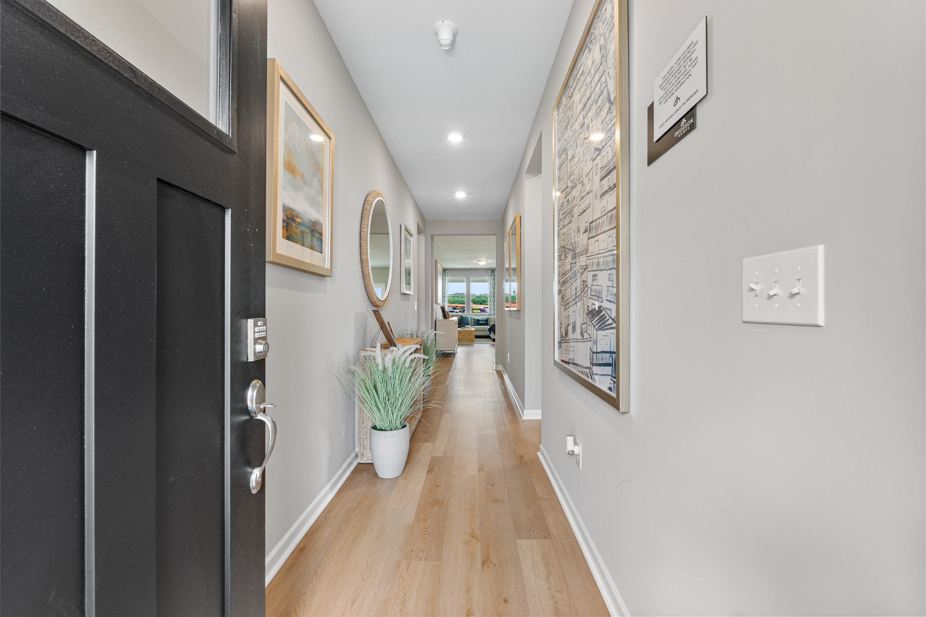 Spacious entry hallway in Forest Glen Hazel Green AL home with light oak floors, gray walls, artwork and potted plant