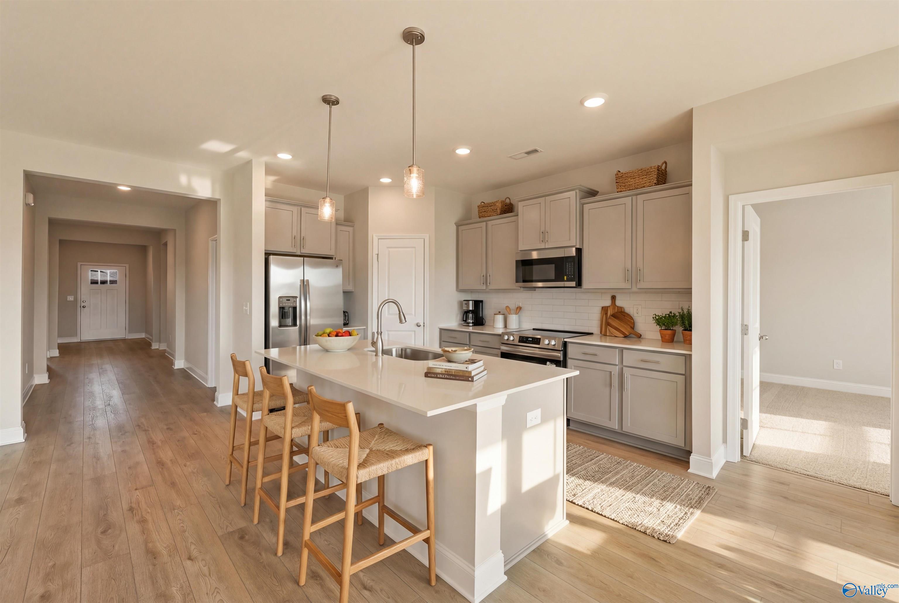 Open-concept kitchen with white quartz island, gray cabinets, stainless appliances in The Everett 4-bedroom home, Hazel Green, AL