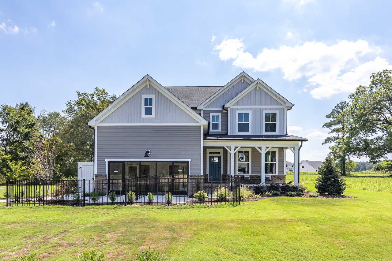 Gray modern farmhouse home exterior at Wellers Knoll in Lillington NC with covered porch, attached garage, and lush green lawn
