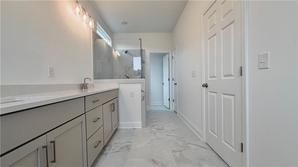 Modern master bathroom with dual vanity and walk-in shower in The Glenwood A floor plan at Wehunt Meadows, Hoschton, GA.