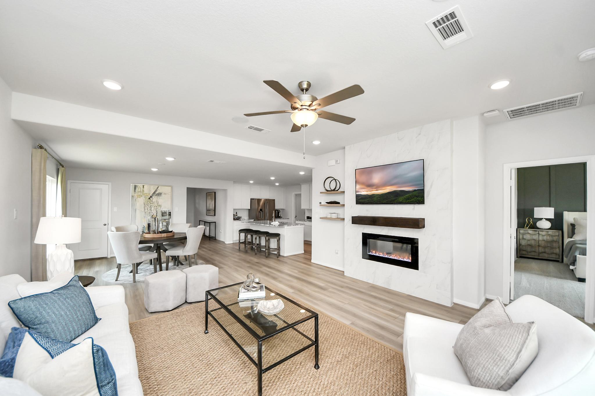 Open-concept living room at Sunterra in Katy, TX by Davidson Homes featuring a marble fireplace and modern kitchen.
