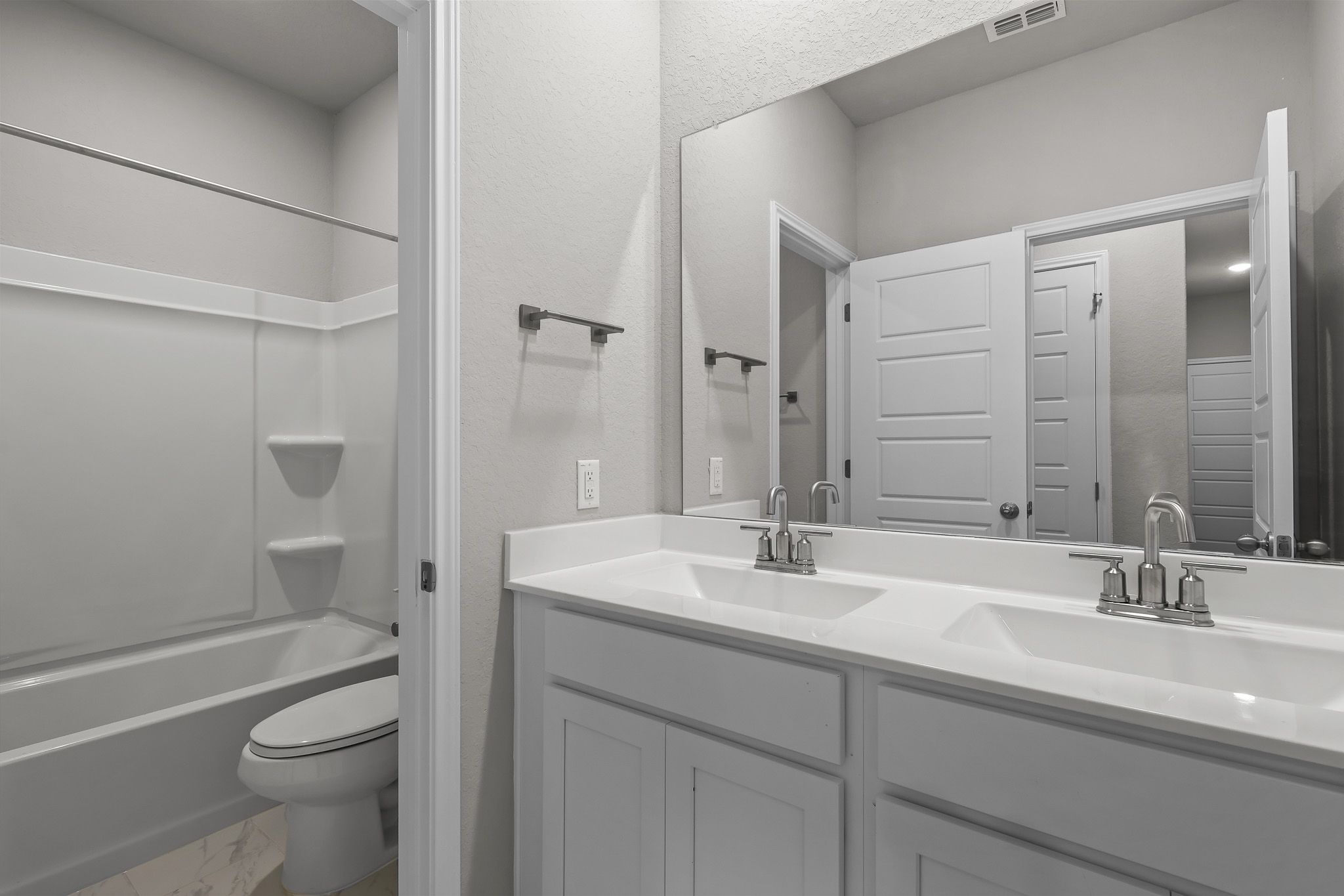Modern bathroom in The Colorado B featuring a dual-sink vanity, large mirror, and a tub-shower combo.