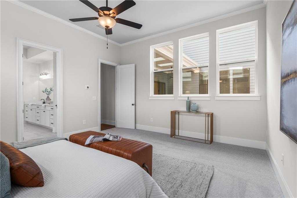 Spacious master bedroom suite with en-suite bath, king bed, ceiling fan, and large windows in Davidson Homes The Seaside B, Woodstock, GA