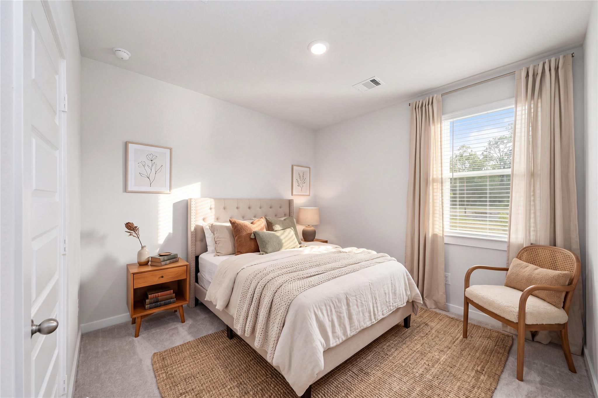 Bright neutral bedroom with upholstered headboard and accent chair in Davidson Homes' The Frio F, Liberty Estates, Cleveland, Texas