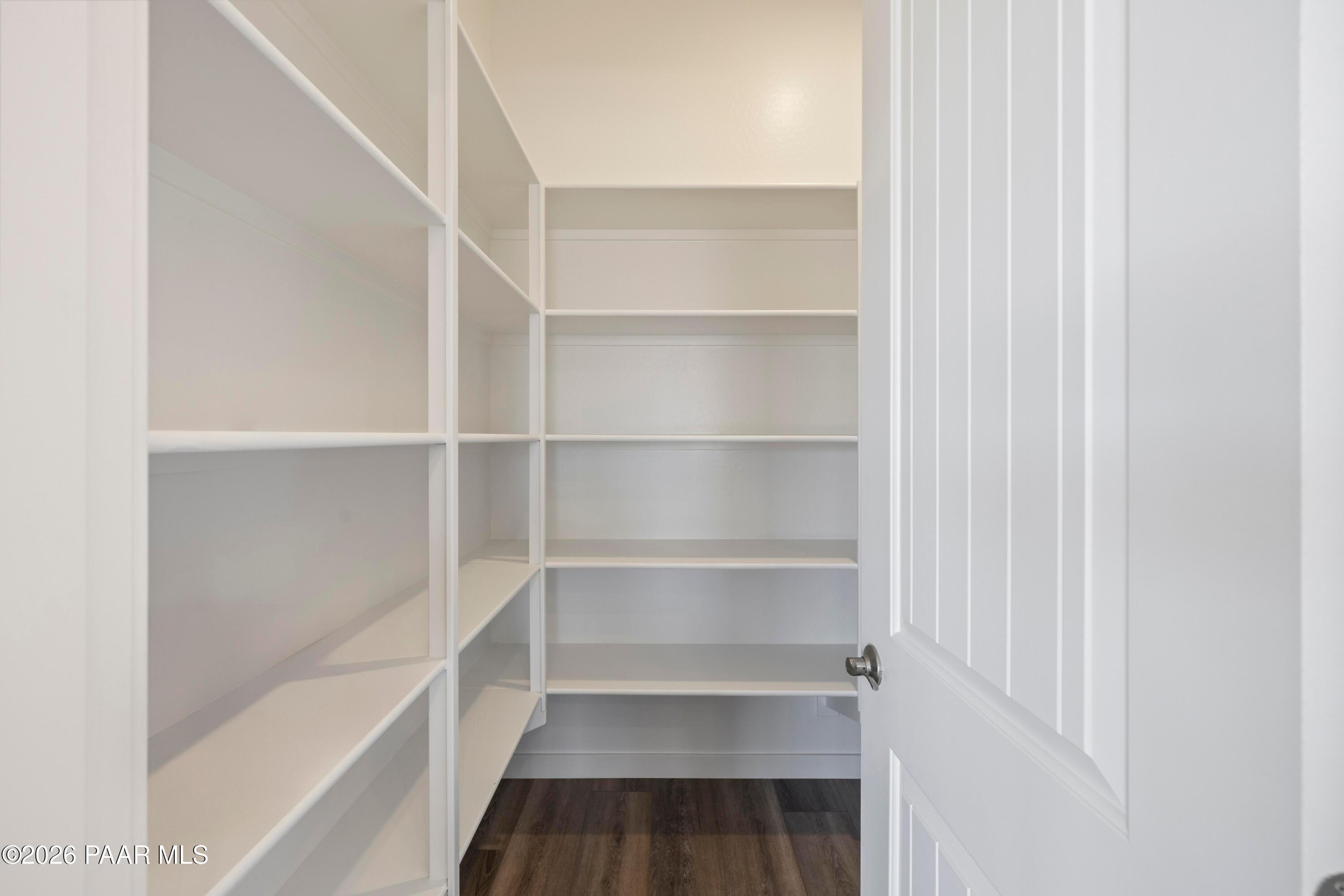 Spacious walk-in closet with white built-in shelves and hardwood floors in Davidson Homes The Soleil E, Prescott, Arizona