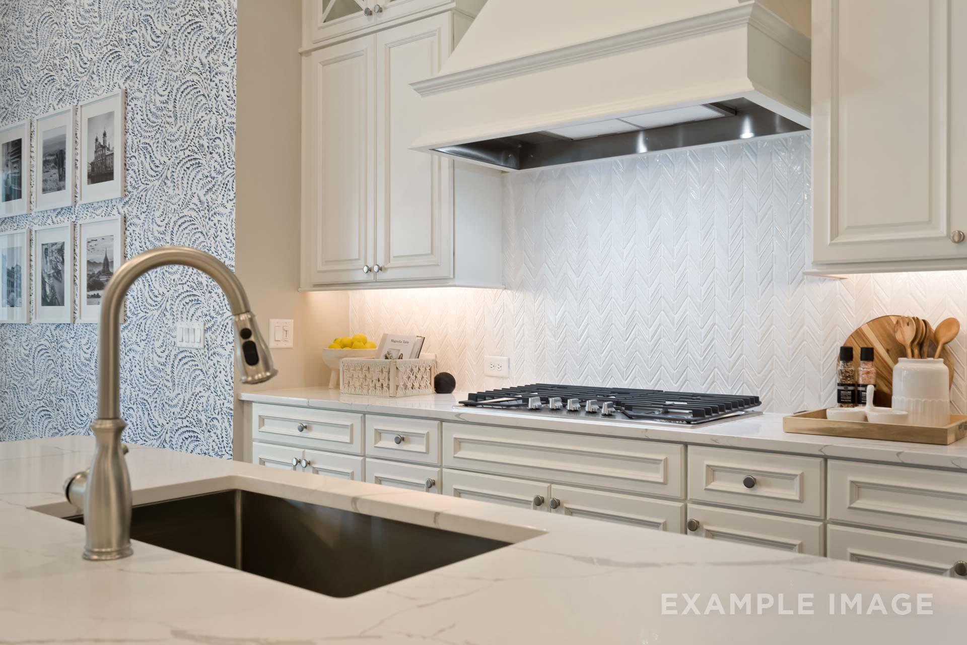 Spacious gourmet kitchen in The Seaside C featuring white shaker cabinets, stainless steel sink, gas range, and herringbone backsplash