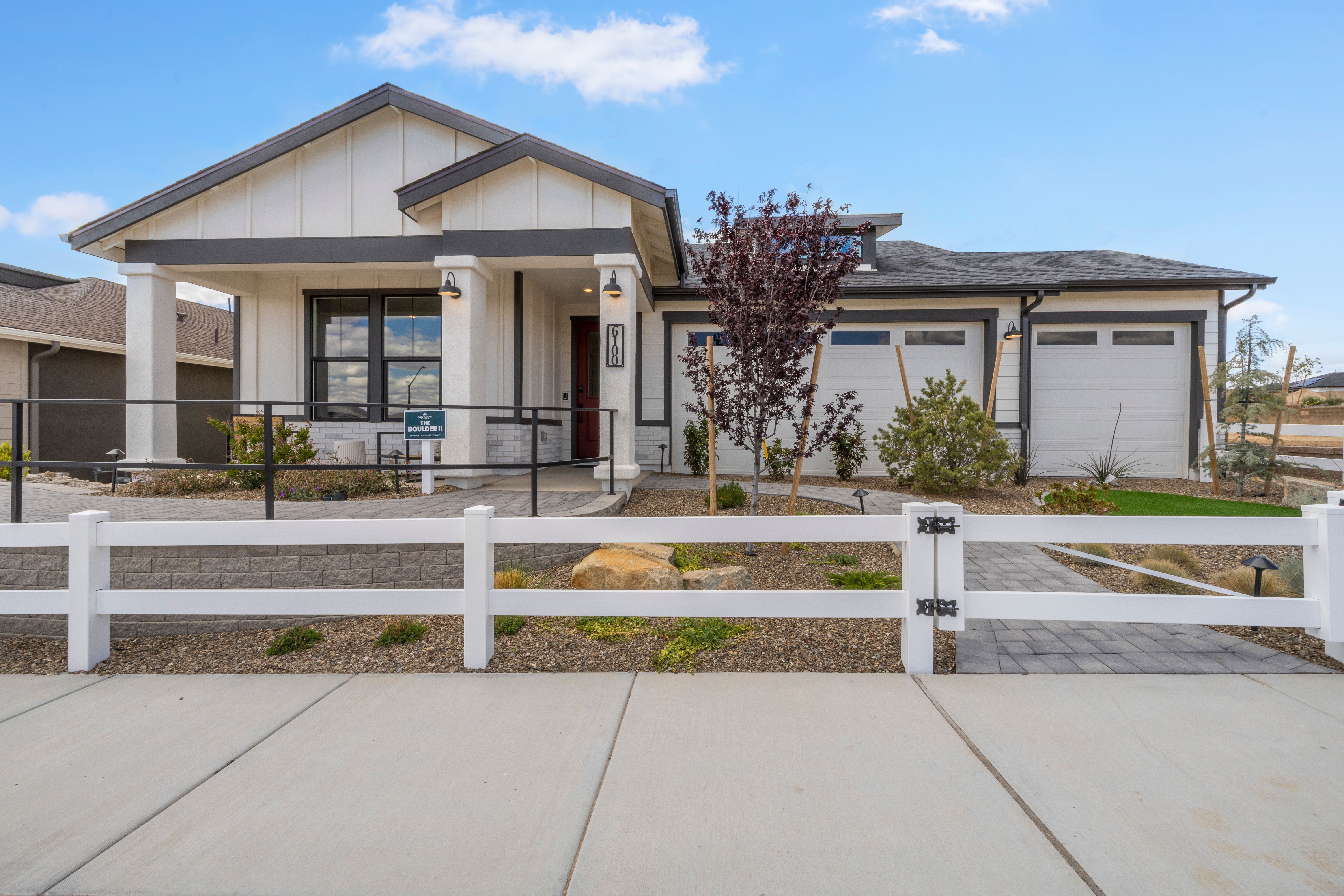 Modern ranch home exterior at South Ranch Western Collection in Prescott AZ with covered porch, purple leaf tree and white rail fence