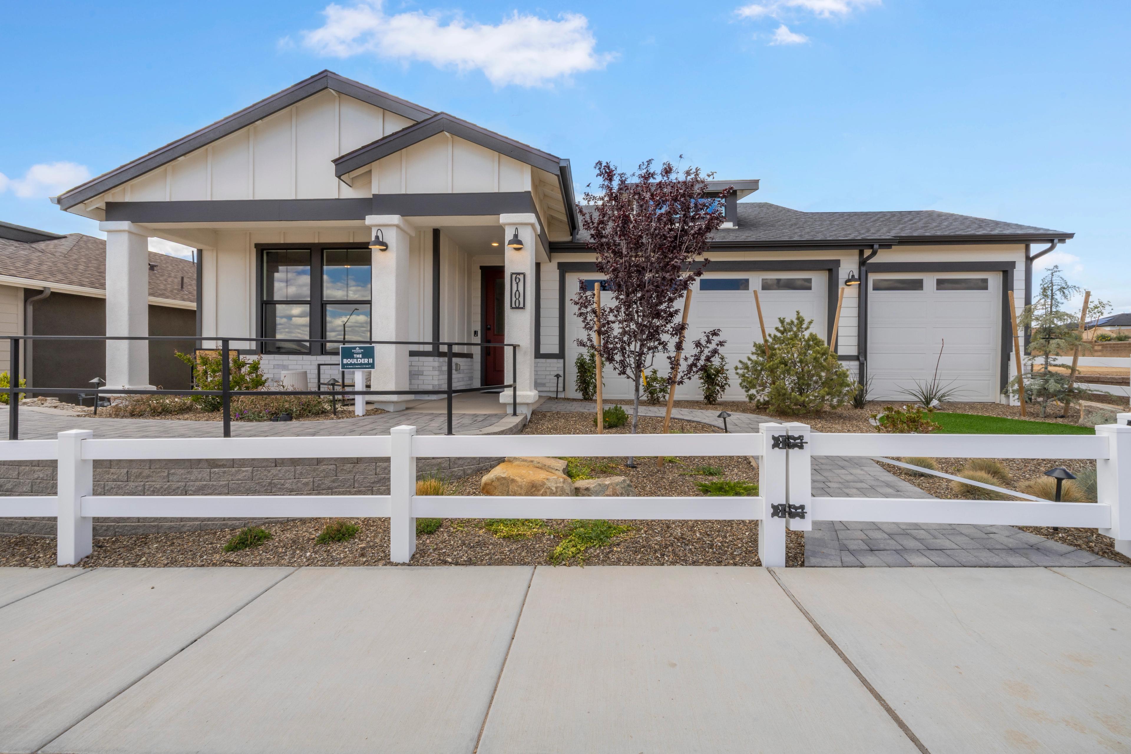 Modern ranch home exterior at South Ranch Western Collection in Prescott AZ with covered porch, purple leaf tree and white rail fence