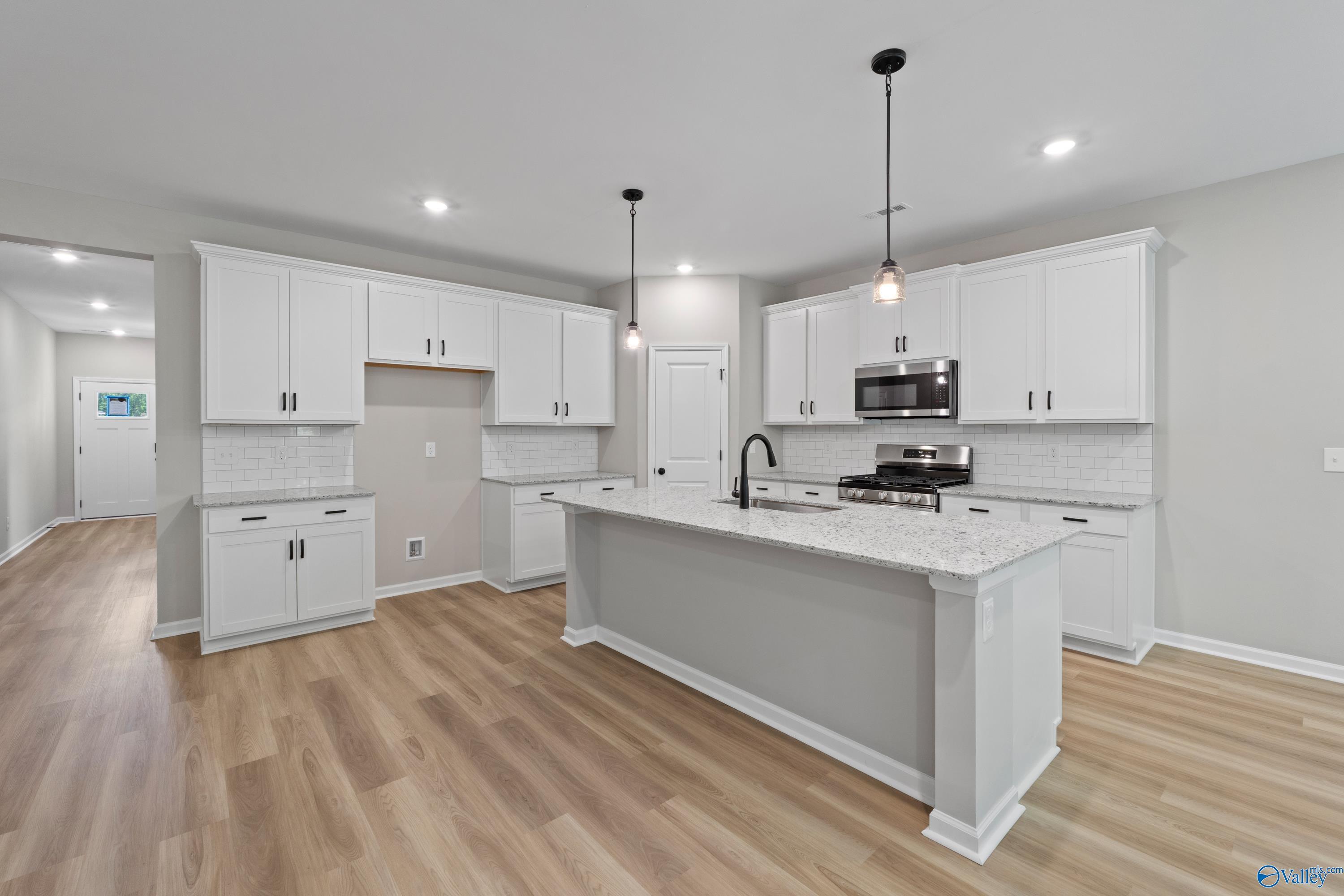 Modern white kitchen with quartz island, stainless appliances, subway tile backsplash in Davidson Homes The Phoenix, Hazel Green, AL