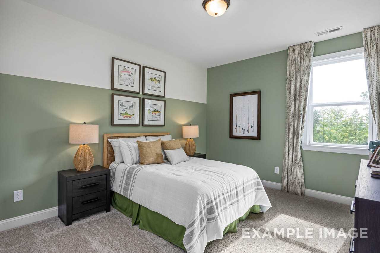 Serene bedroom at Wendell Ridge in Wendell NC by Davidson Homes with sage green accent wall, king bed, and nature artwork