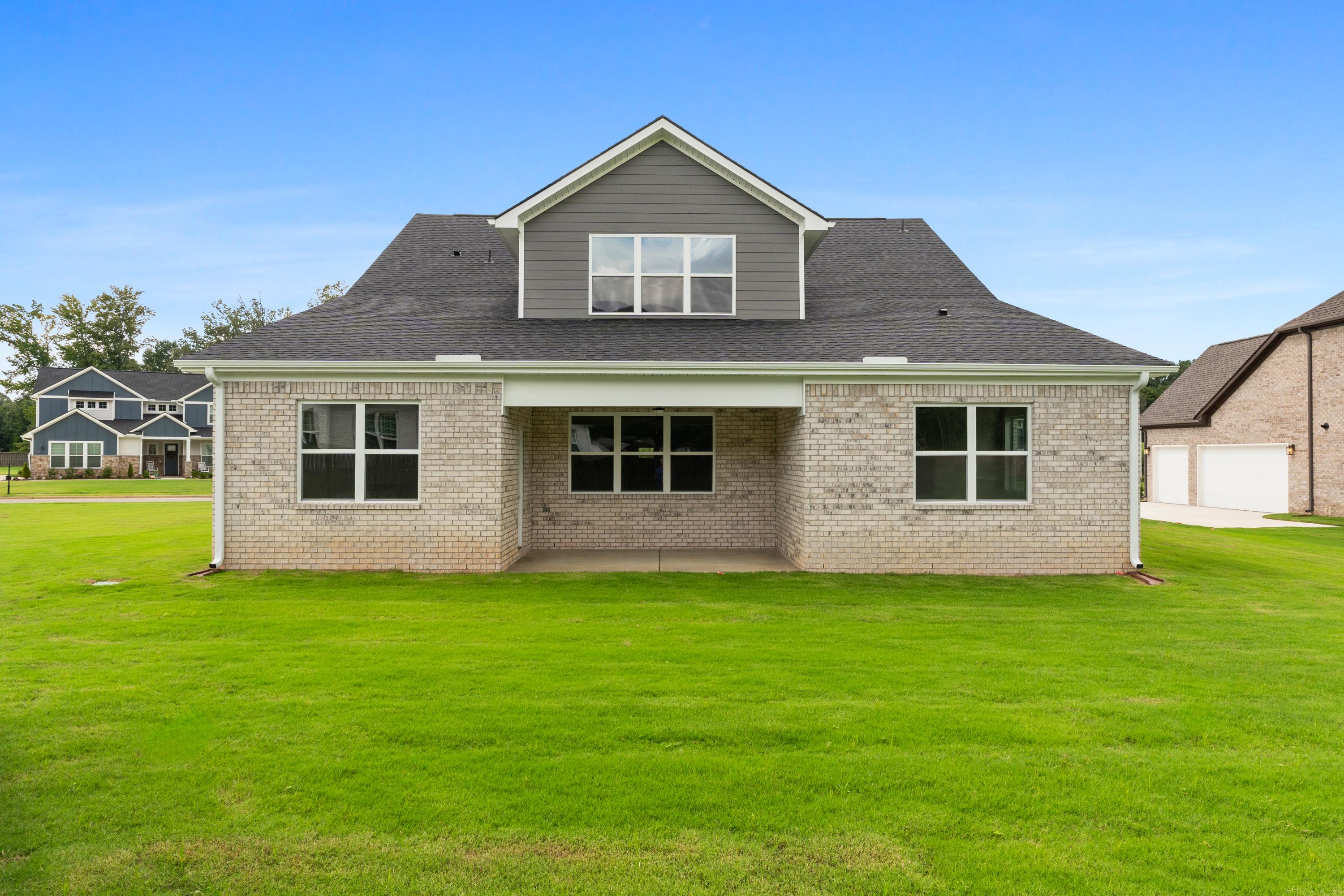 The Oxford two-story brick home elevation with gray roof, covered front porch, large windows, and lush green lawn in Owens Cross Roads