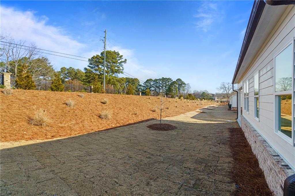 Side view of The Edison A 3-bedroom home with gravel pathway and pine straw landscaping in Kelly Preserve, Loganville, Georgia