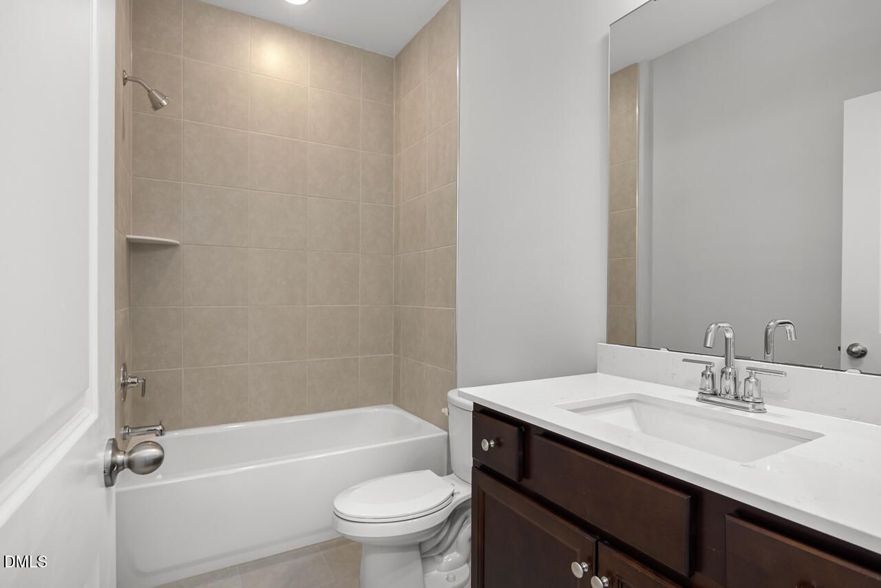 Modern bathroom with tub-shower combo and dark vanity in The Adalynn A floor plan at Gregory Village, Lillington, NC.