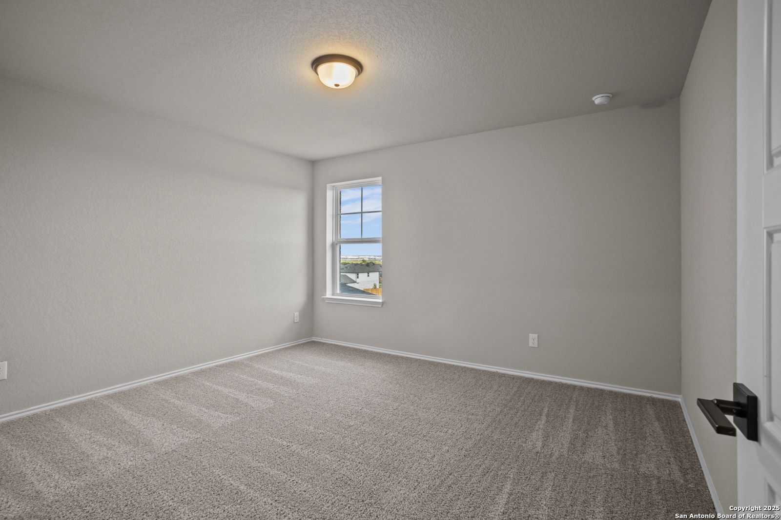 Bright empty bedroom with neutral walls, carpet flooring, and large window in Davidson Homes The Douglas F, San Antonio, Texas