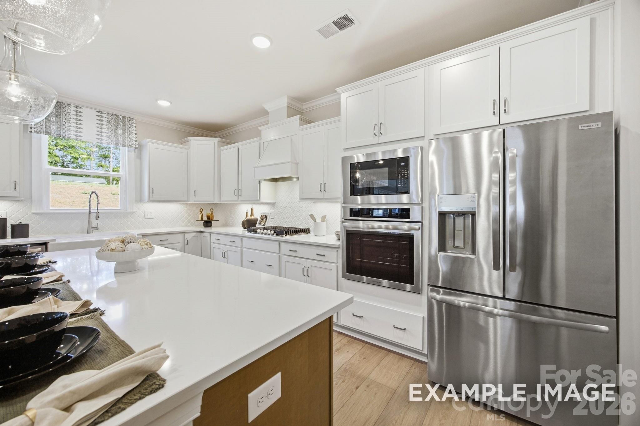 Modern kitchen with white cabinets, quartz countertops, and stainless appliances in The Hickory B II floor plan, Mooresville.