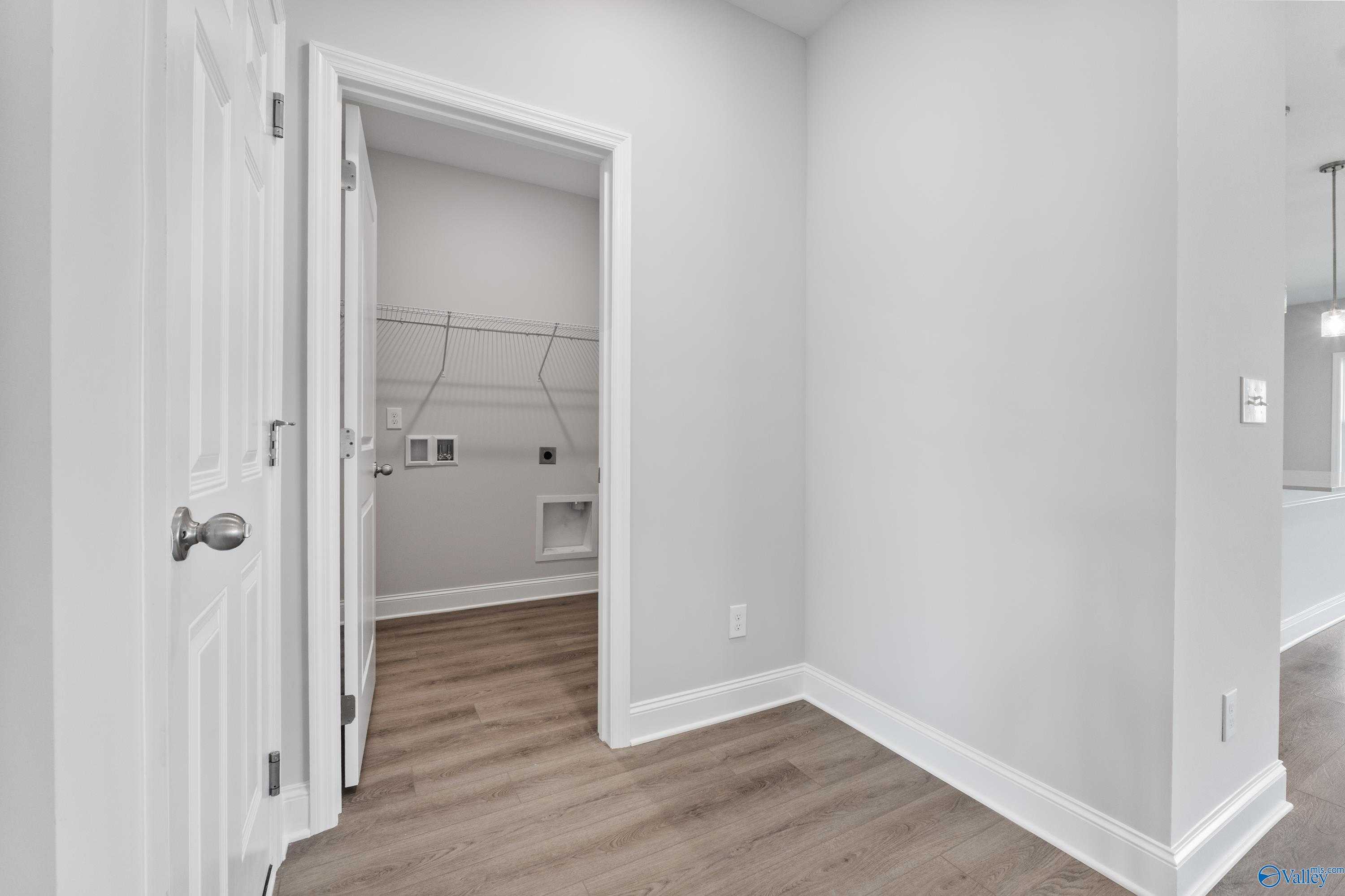 Modern laundry room with washer dryer hookups, utility sink, gray walls, wood flooring in Davidson Homes Franklin C, Toney Alabama