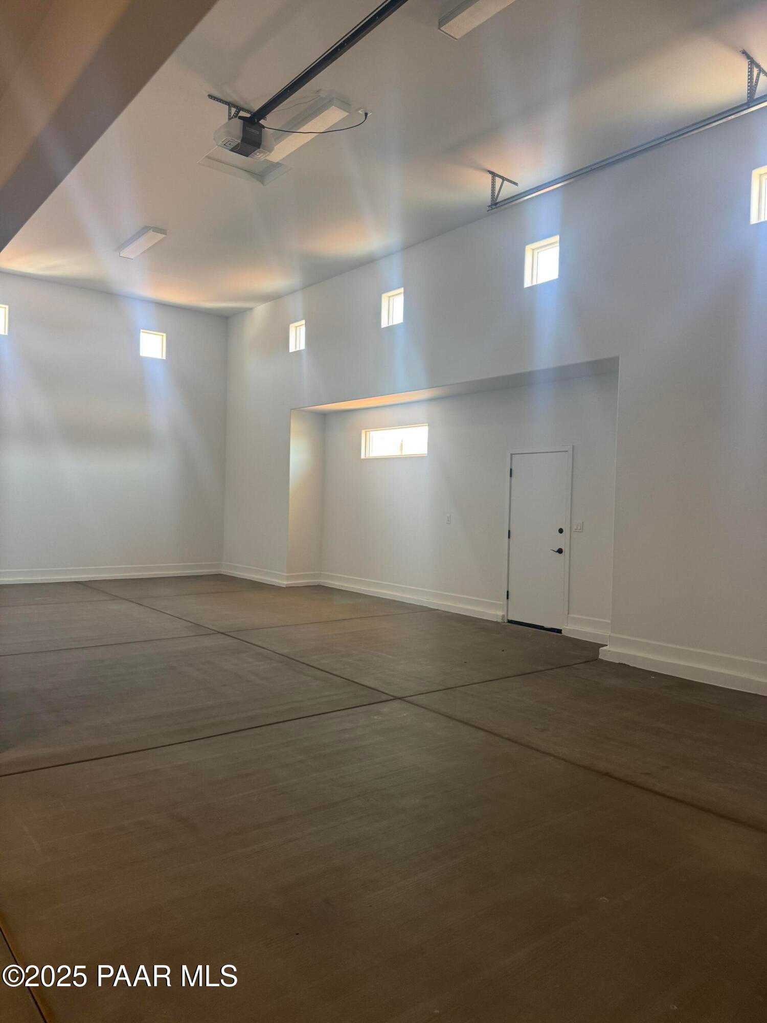 Spacious 2-car garage with polished concrete floor, clerestory windows, and overhead lighting in Evermore Homes The Summit B, Prescott Valley, Arizona