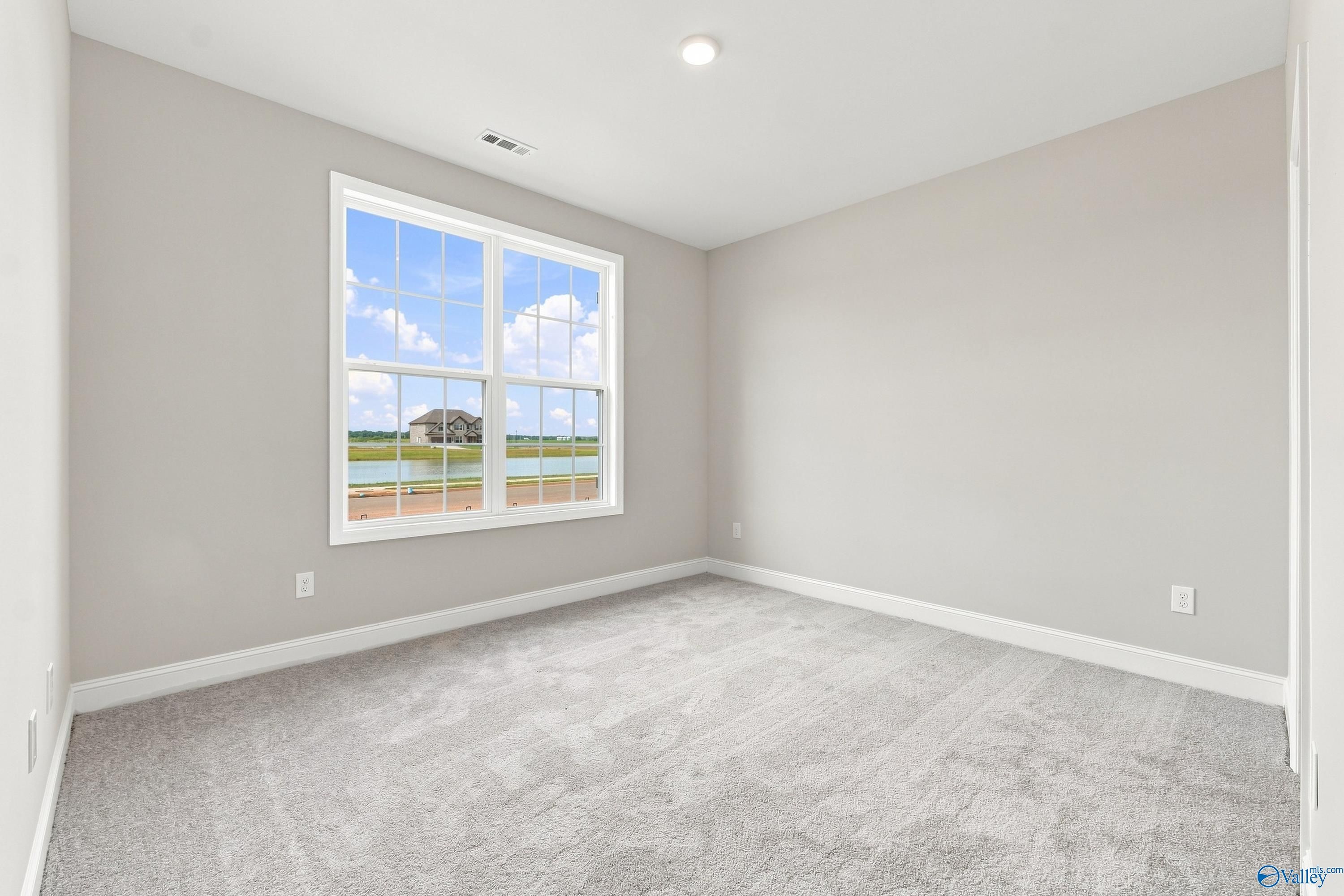 Spacious bedroom with carpet and large window view in The Rockford B floor plan at Kendall Downs, Toney, Alabama.